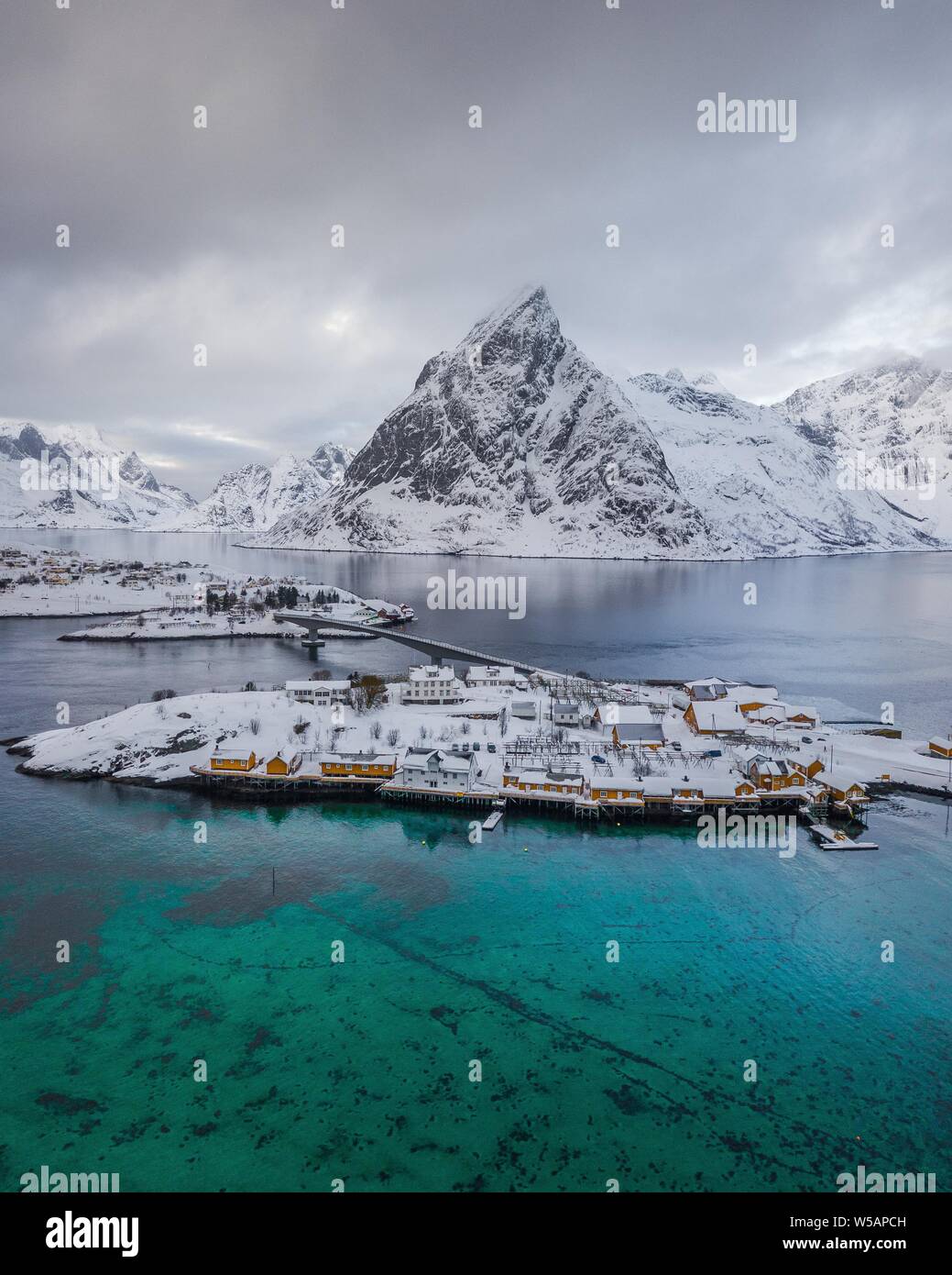 Belbe Pfahlbauten am türkisblauen Meer im Winter, Sakrisoy, Drone, Lofoten, Norwegen Stockfoto