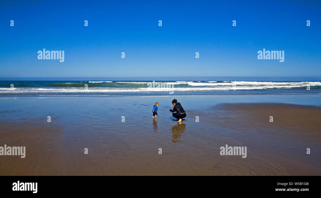 Eine Mutter mit ihrem kleinen Sohn spielen an einem Sandstrand auf der Oregon Küste in der Nähe von Lincoln City, Oregon. Stockfoto