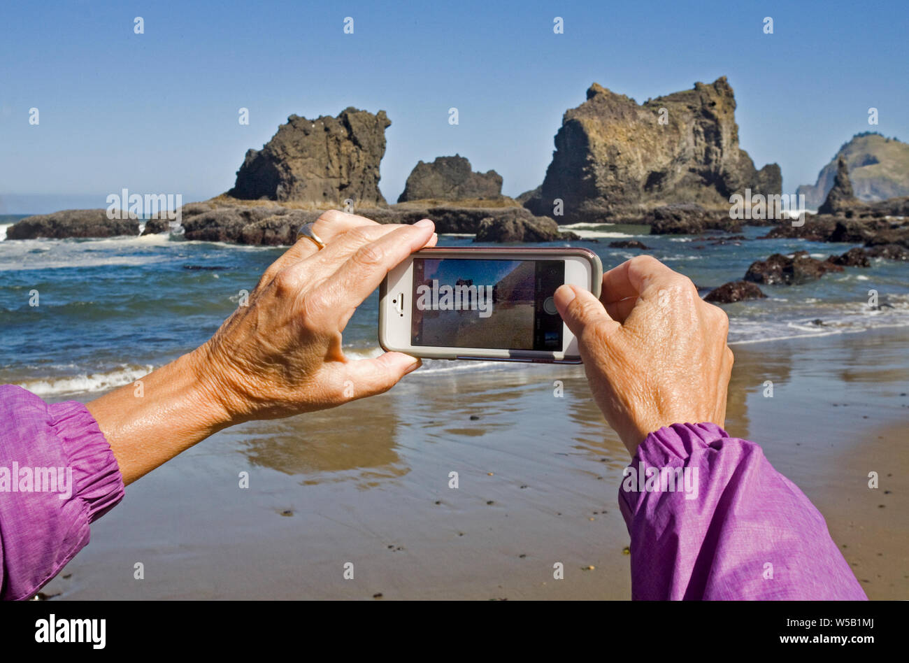 Eine teourist nimmt ein Foto auf den Pazifischen Ozean mit Ihrem Iphone in der Nähe von Lincoln City, Oregon, auf der Oregon Pazifikküste. Stockfoto