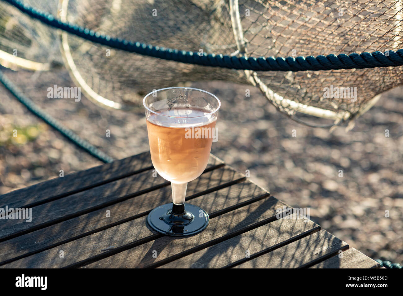 Glas Rose Wein mit einem Fischernetz im Hintergrund Stockfoto