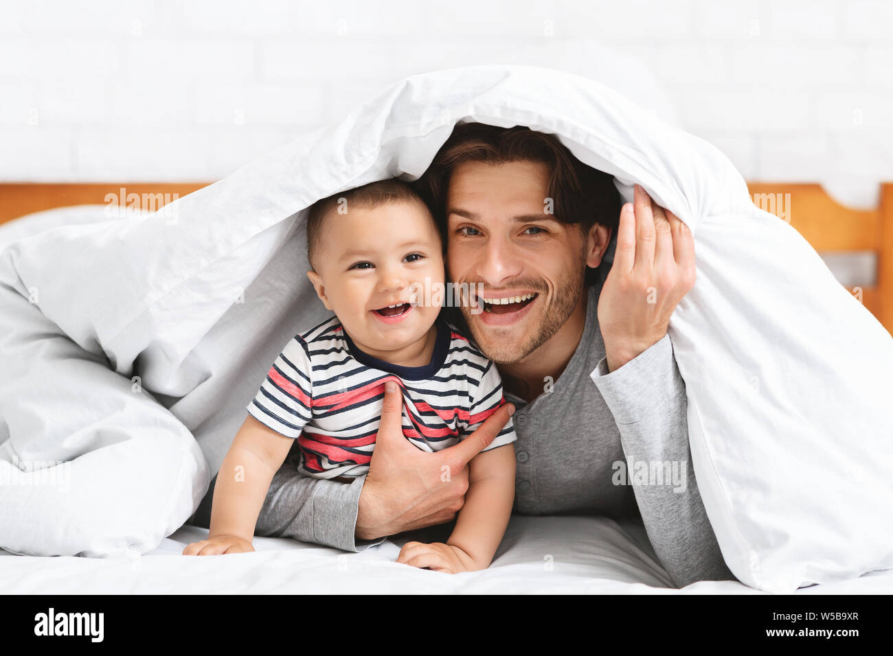 Kaukasische Mann verstecken mit Baby im Bett unter der Decke Stockfoto