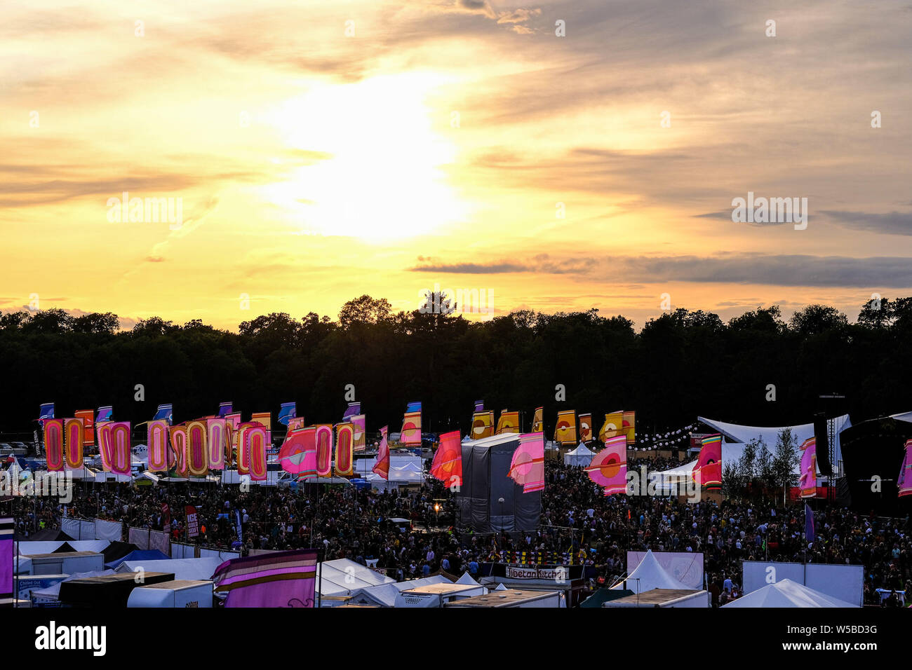 Malmesbury, Wiltshire, UK. 26. Juli 2019. Die Sonne über dem WOMAD-Festival (Welt der Musik, Kunst und Tanz) am Samstag, 27. Juli 2019 in Charlton Park, Malmesbury. An einem Tag des durchwachsenes Wetter, die Wolken lassen die Sonne durch, wie es setzt. Bild von Julie Edwards Stockfoto