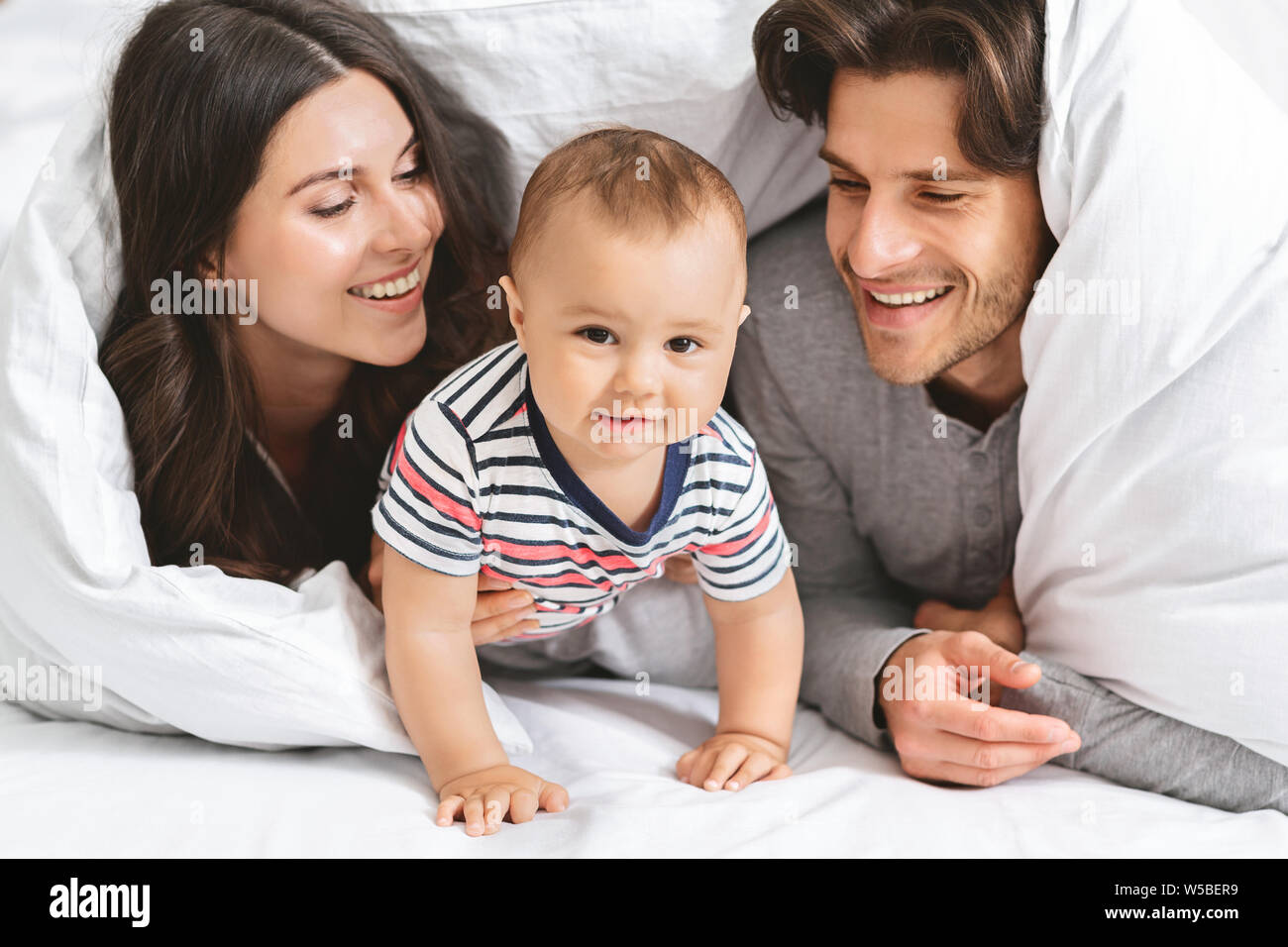 Happy Family spielen Versteck unter der Decke im Bett Stockfoto