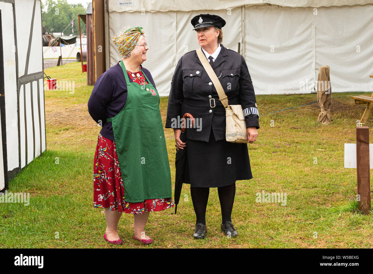 Krieg und Frieden Revival 2019, Paddock Wood Hop Farm. Zwei Damen im Jahre 1940 das Kostüm ein Gespräch. Eine Dame in Uniform. Stockfoto