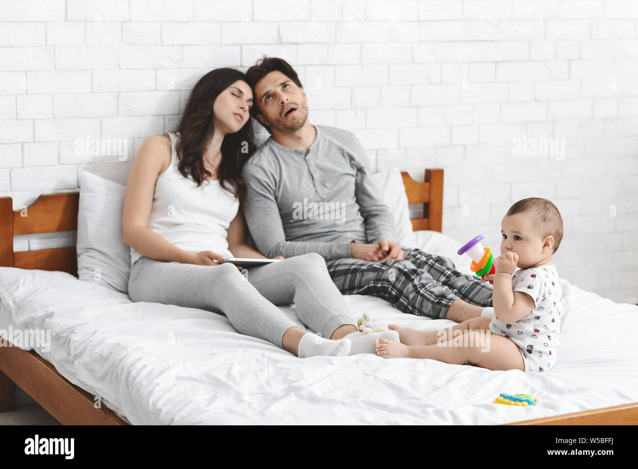 Müde tausendjährigen Eltern sitzen auf dem Bett und schlafen wollen Stockfoto