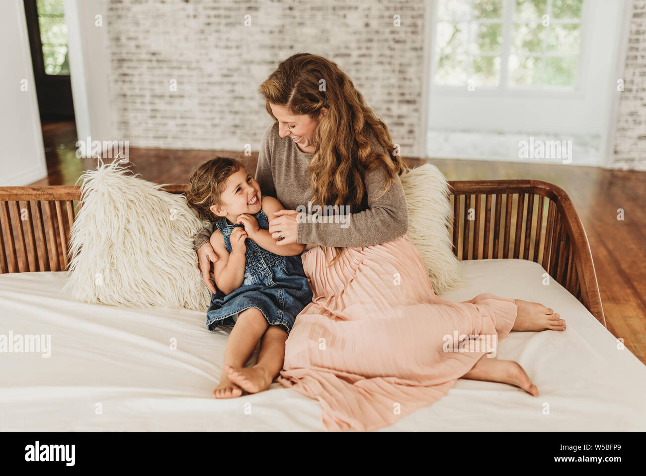 Mutter und Tochter sitzen auf der Couch kitzeln und Lachen im Studio Stockfoto