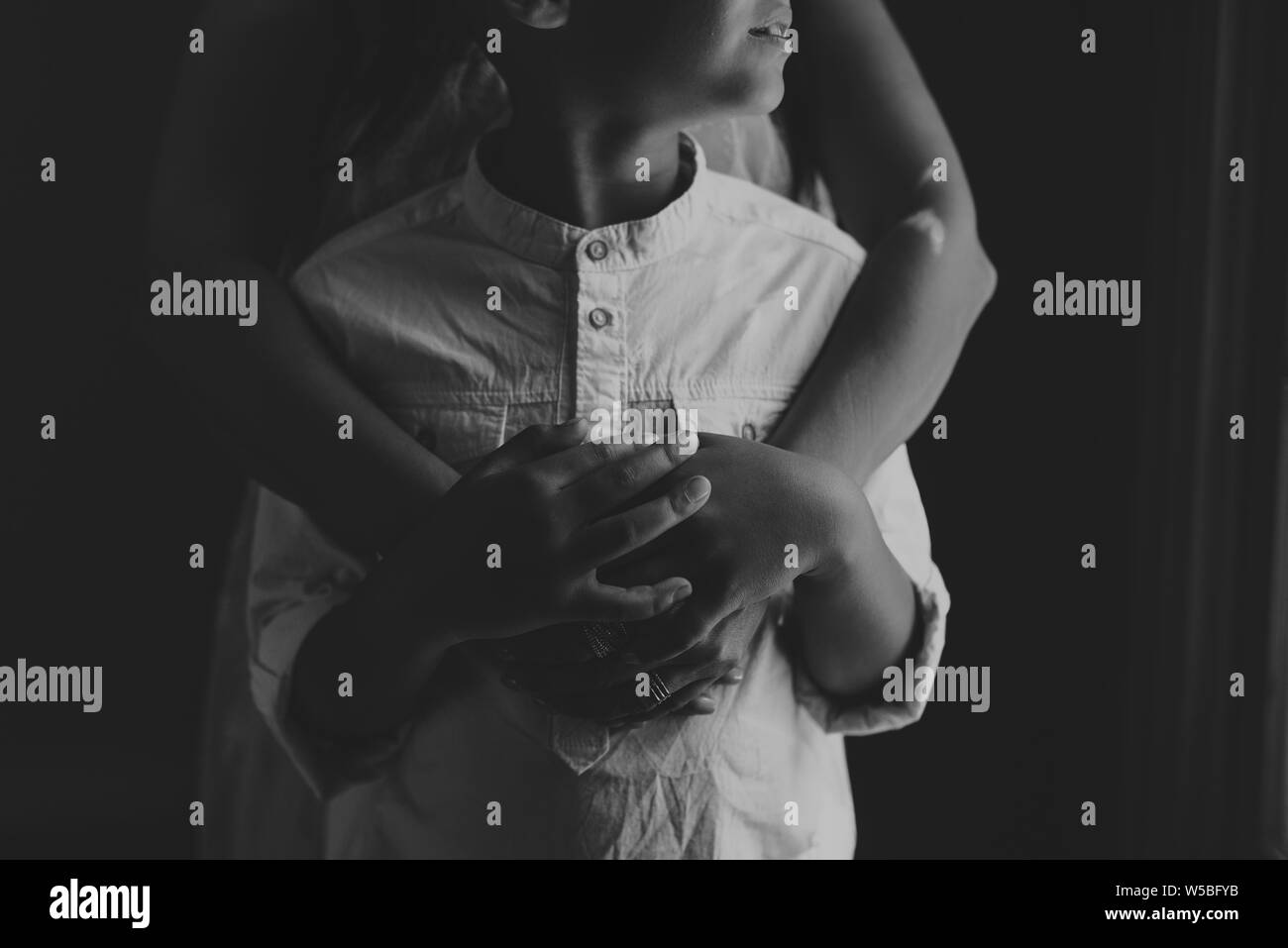 Schwarz-weiß Bild von Mutter und Sohn umarmen im Studio Stockfoto