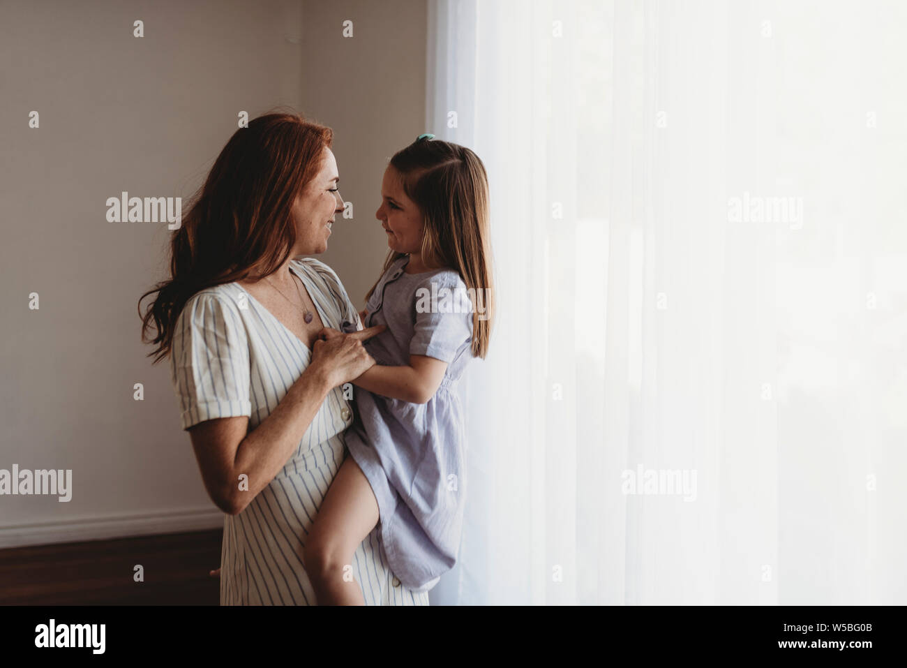Seitenansicht der jungen Mutter, die junge Tochter und an ihrem Lächeln Stockfoto