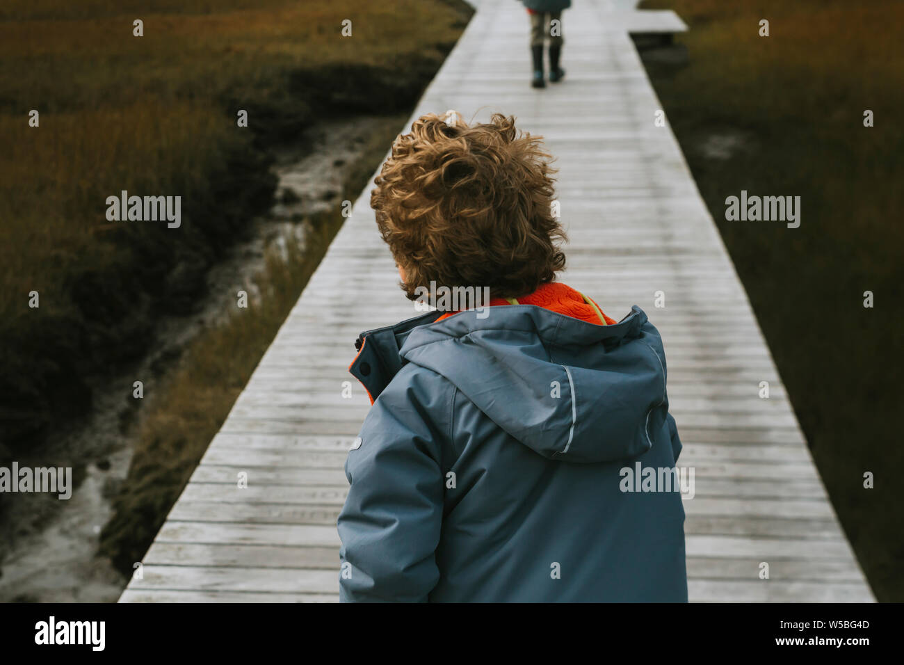 Ansicht der Rückseite des Kindes mit dem lockigen Haar am Boardwalk Stockfoto