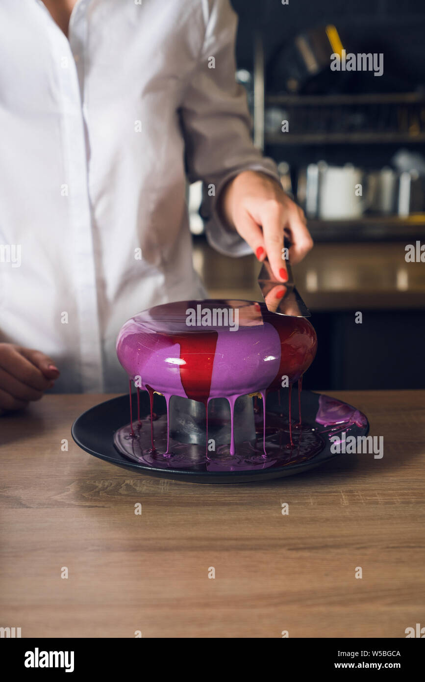 Women's Hände, die Spachtel und glättende Creme auf einem Kuchen. Stockfoto