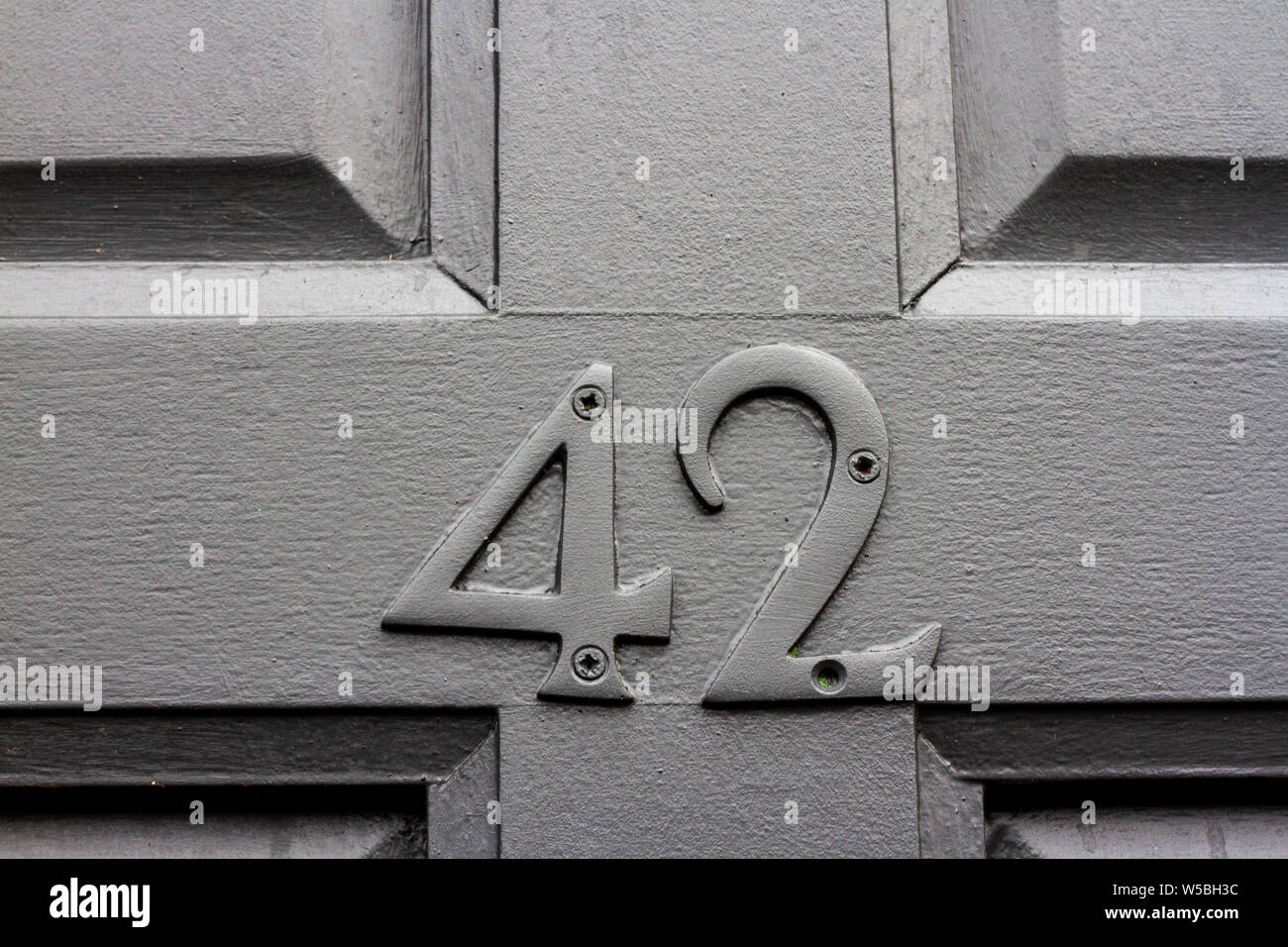 Elegante graue Haus Nummer 42 mit vierzig zwei in der gleichen Farbe wie die hölzerne Tür Stockfoto