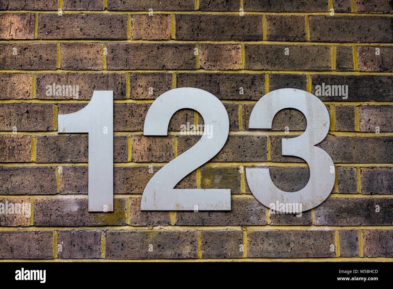 Haus Nummer 123 auf einem gelben Wand Stockfoto
