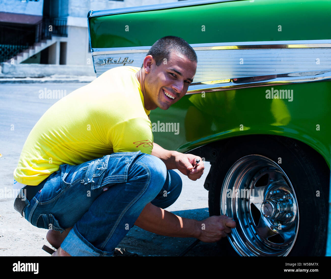Kubanische Mechaniker lächelt, während sie Luft in die Reifen seines klassischen Kubanischen Auto Stockfoto