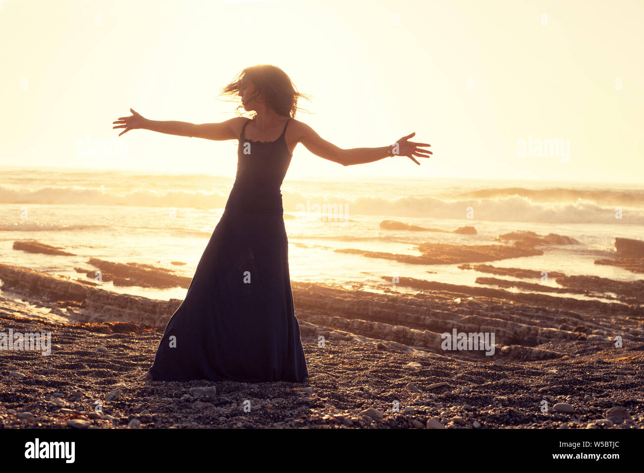Dankbar, romantische Frau am Strand bei Sonnenuntergang. Stockfoto