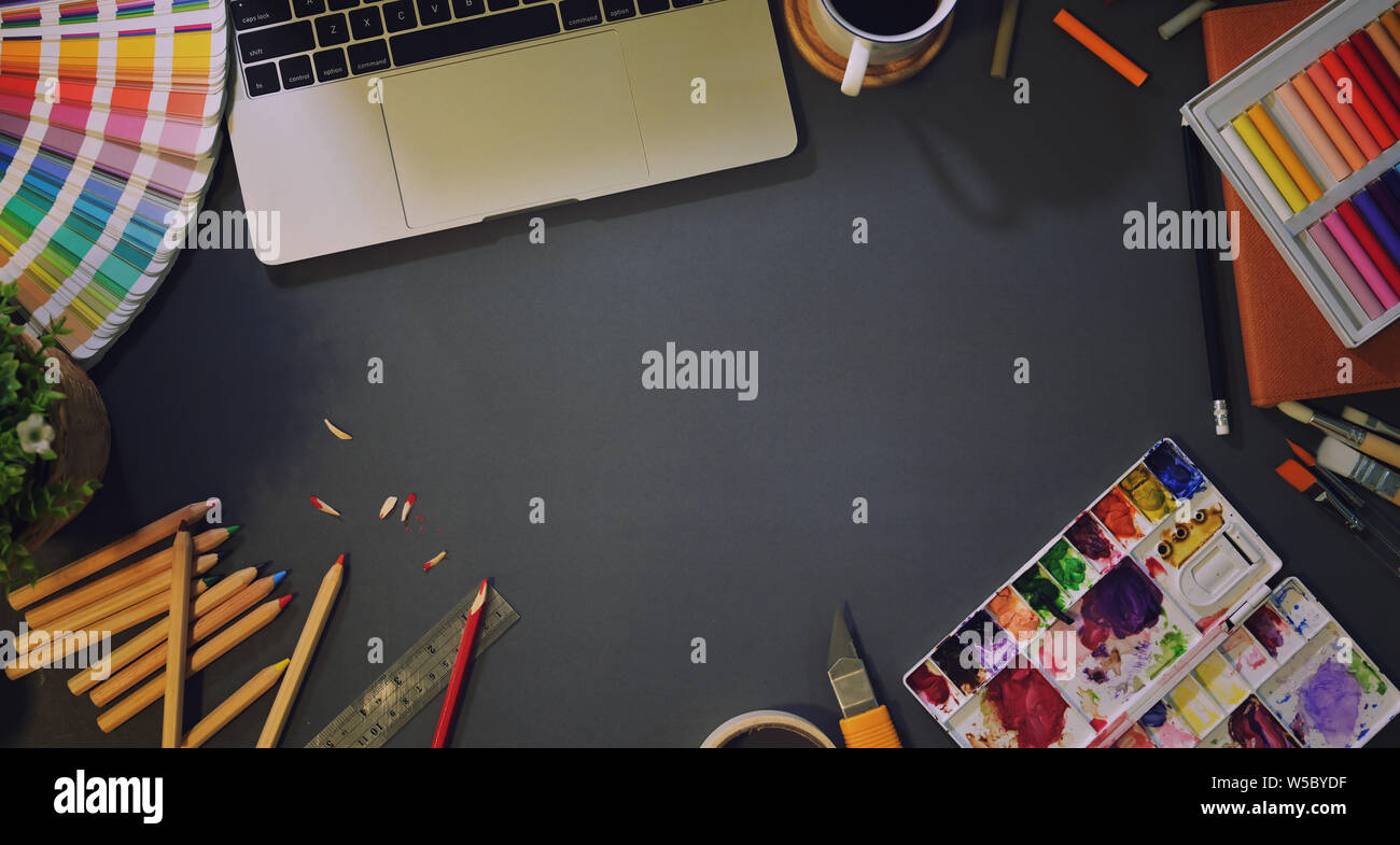 Blick von oben auf die Künstler Creative Studio mit Gemälden, Werkzeuge, Büromaterial und Laptop in dunklen Hintergrund Stockfoto