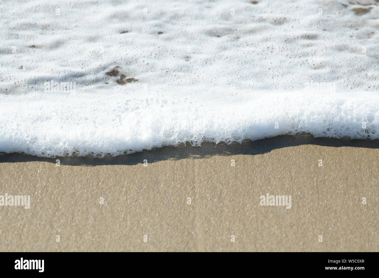 Nahaufnahme, Detail, Schaum und Blasen von abgebrannten Wave waschen über Meer Sand, abstrakt, Hintergrund Stockfoto