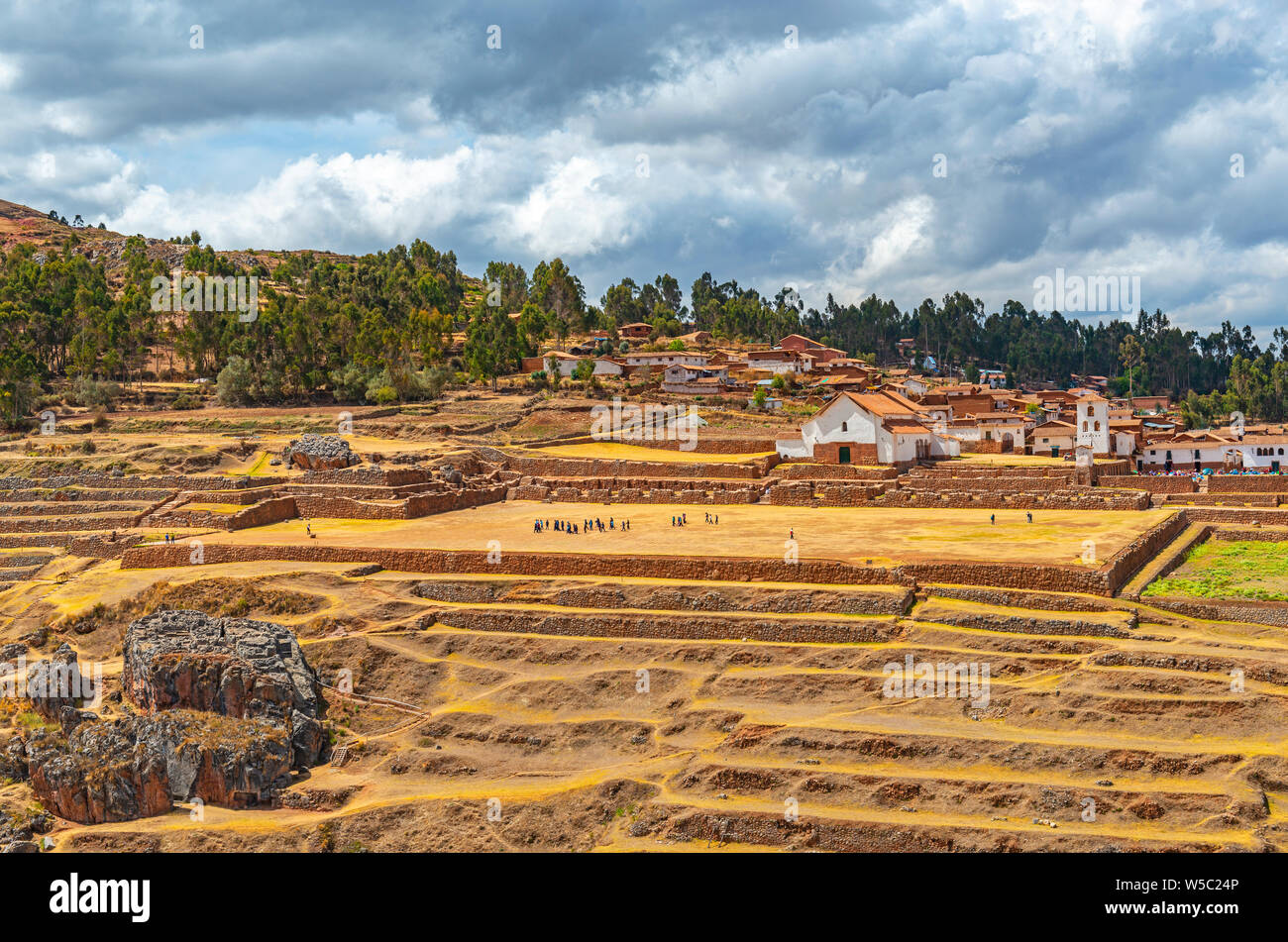 Landwirtschaftlichen Terrassen in der Inka Ruine von Chinchero mit unkenntlich Touristen und Kolonialstil Stadtzentrum mit Kirche, Cusco Region, Peru. Stockfoto