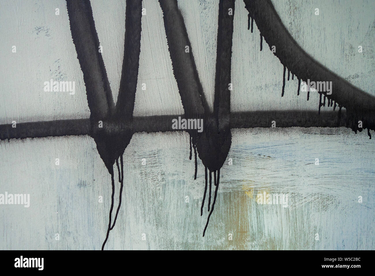 Inky schwarz runny abstrakte Sprühfarbe auf ein unordentliches Wand Stockfoto