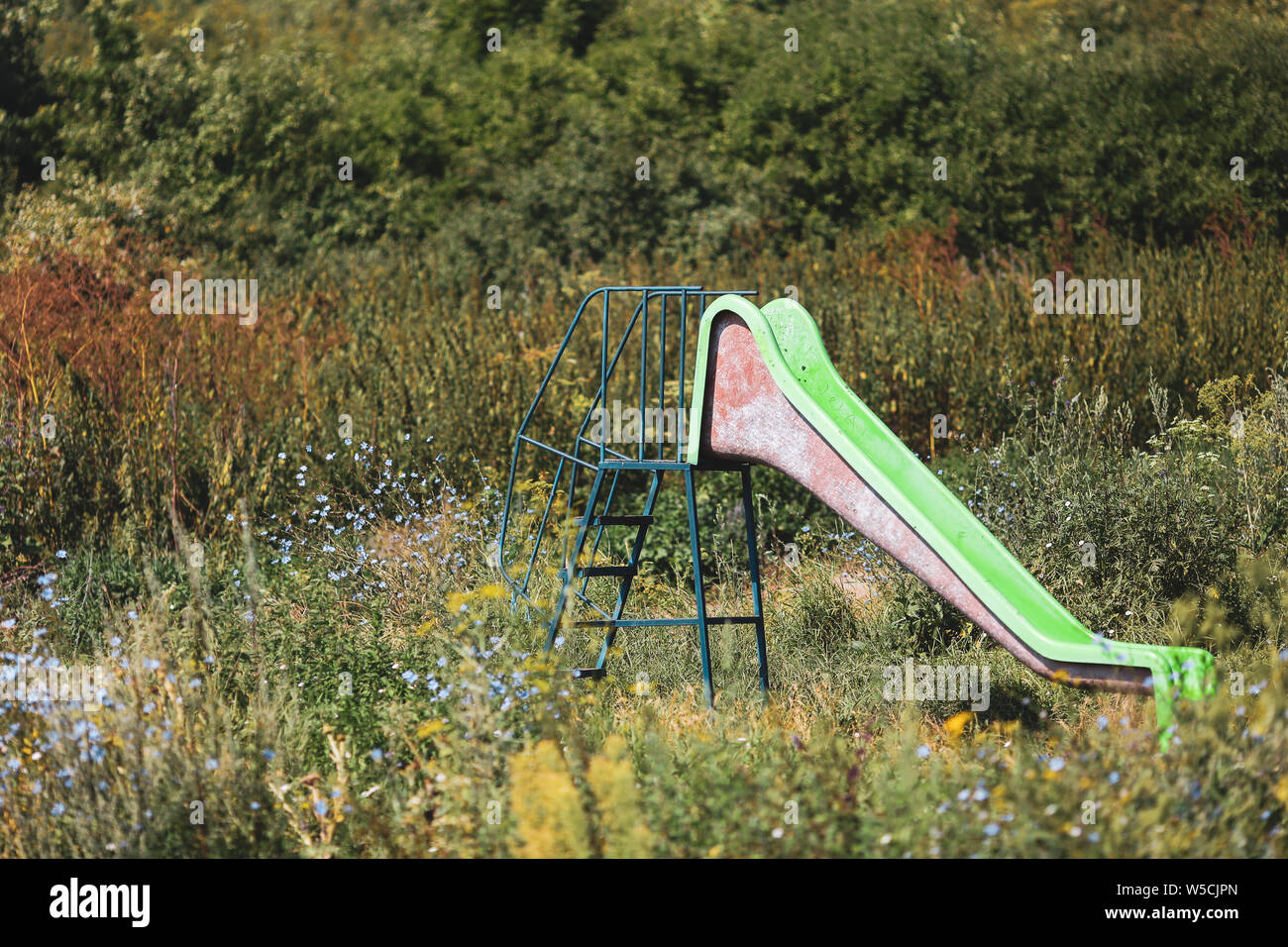 Alten, verlassenen Kinder aus Kunststoff Folie unter schweren Vegetation Stockfoto