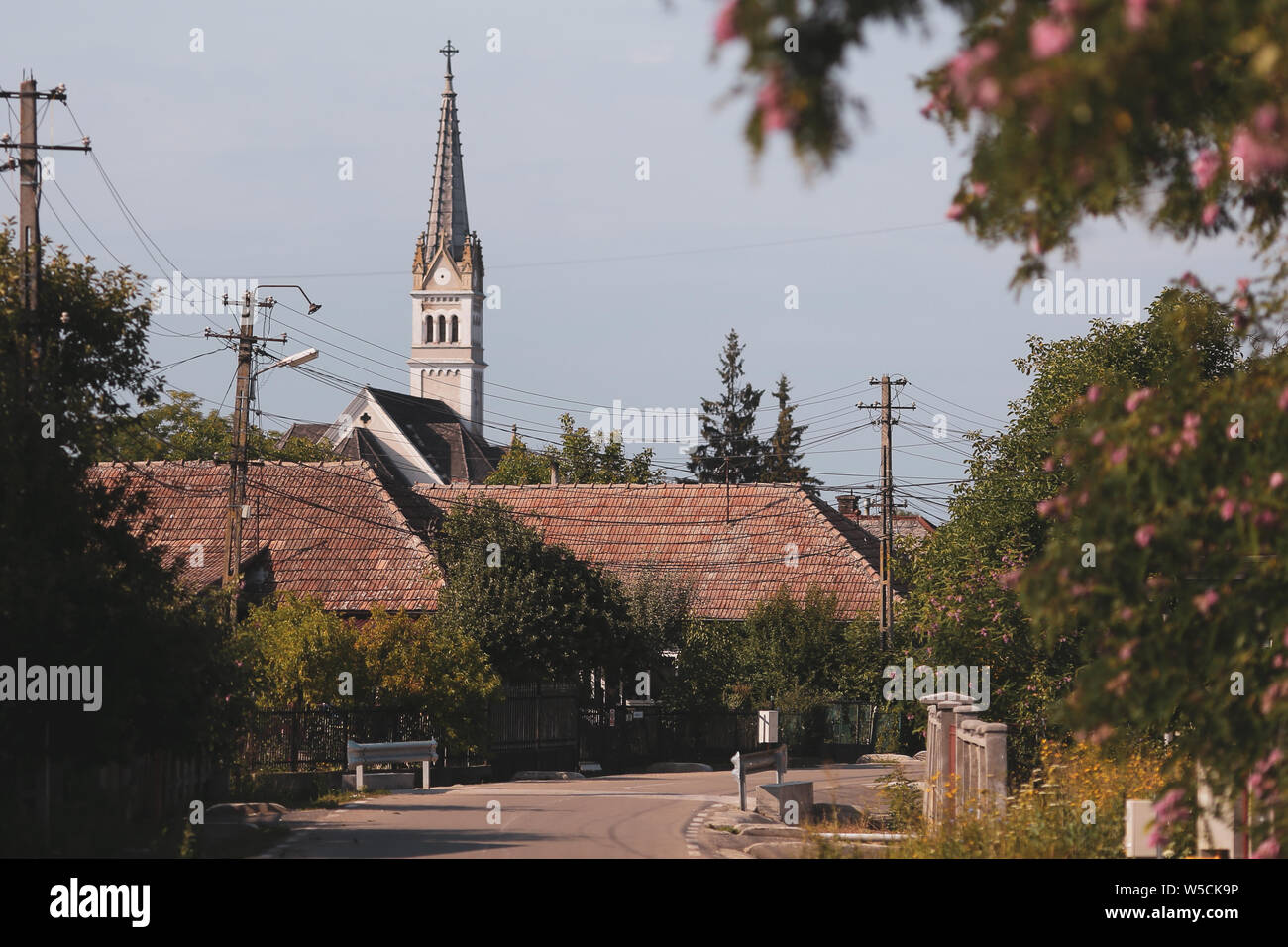 Ländliche Szene aus einem Dorf in Rumänien: Straße, Häuser und eine Kirche Turm im Hintergrund Stockfoto