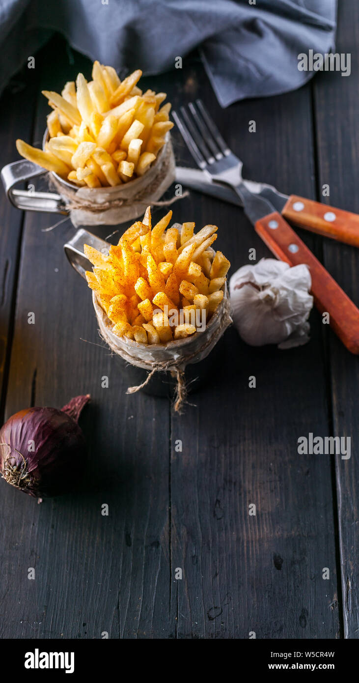 Hausgemachte Pommes Frites, Zwiebeln, Knoblauch, Gabel und Löffel auf dunklen Holztisch. Vertikale essen Banner Stockfoto