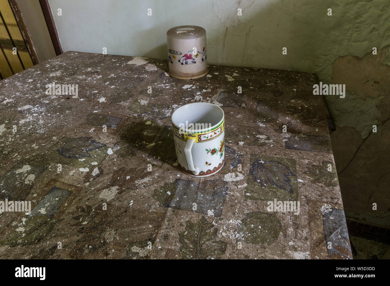 Eine Tasse und eine Kerze auf einem Tisch Leuchte n das verlassene Haus Stockfoto