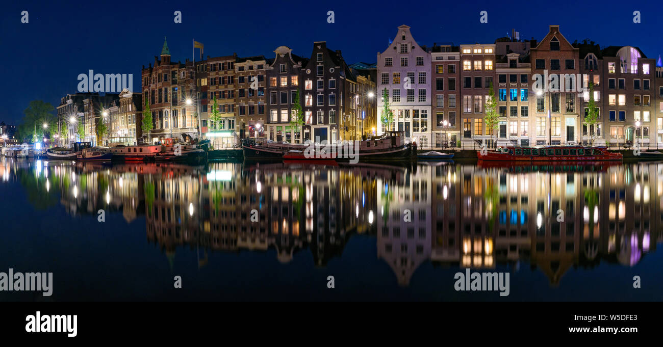Panorama der Reflexion der Gebäude entlang des Kanals in der Nacht in Amsterdam, Niederlande Stockfoto