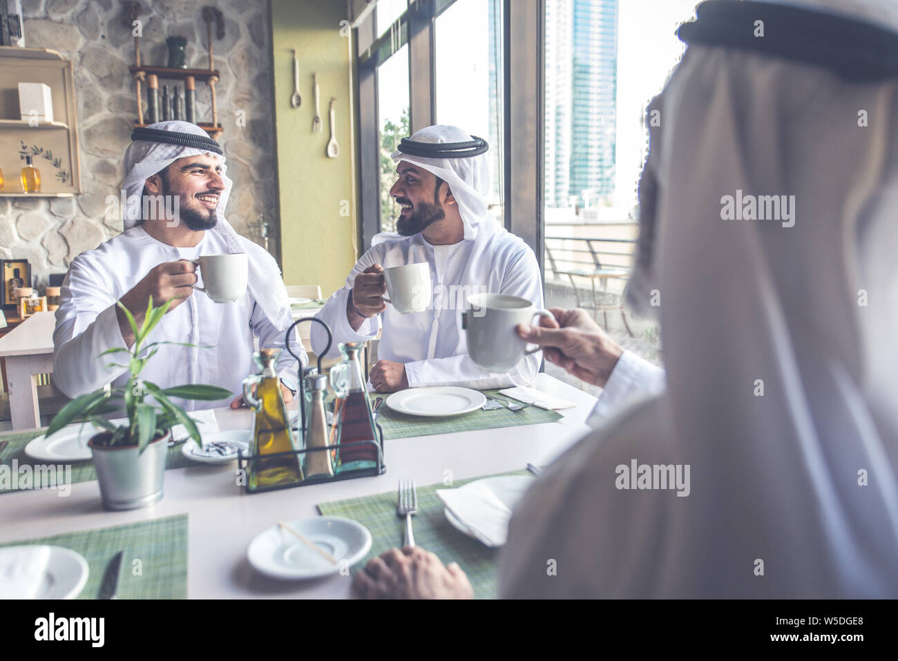 Drei Männer mit einem Tee in Dubai, die traditionelle emiratische Kleidung Stockfoto