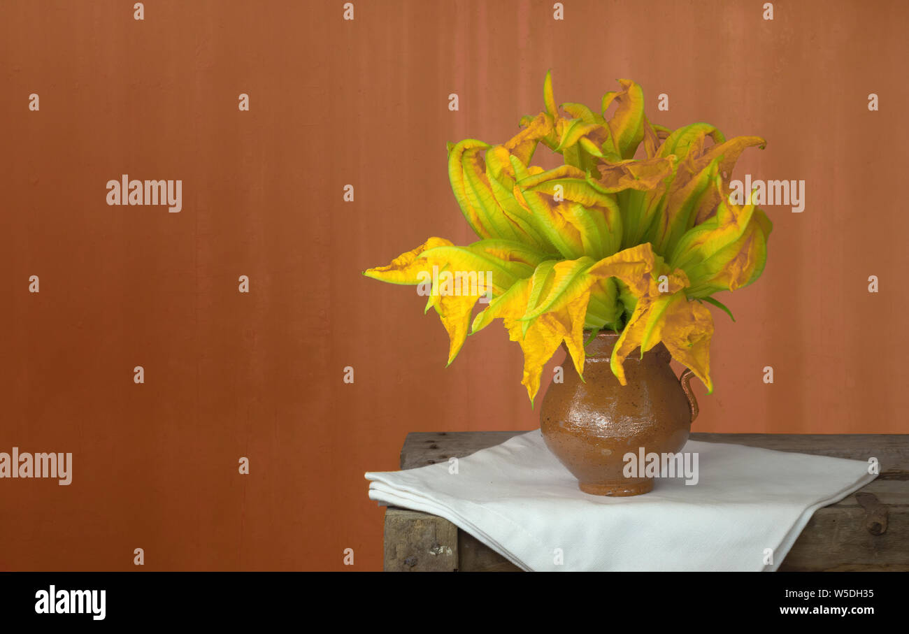 Zucchiniblüten in rustikalem Ambiente, mit einer Kopie. Das zusammengesetzte Bild. Stockfoto