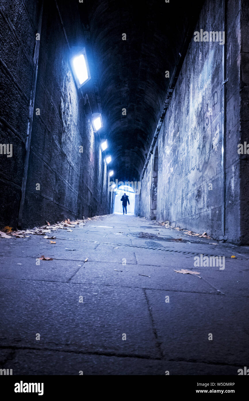 Man Walking durch einen alten Stein Bahnunterführung Tunnel in Newcastle, Tyne und Wear, England, Großbritannien Stockfoto