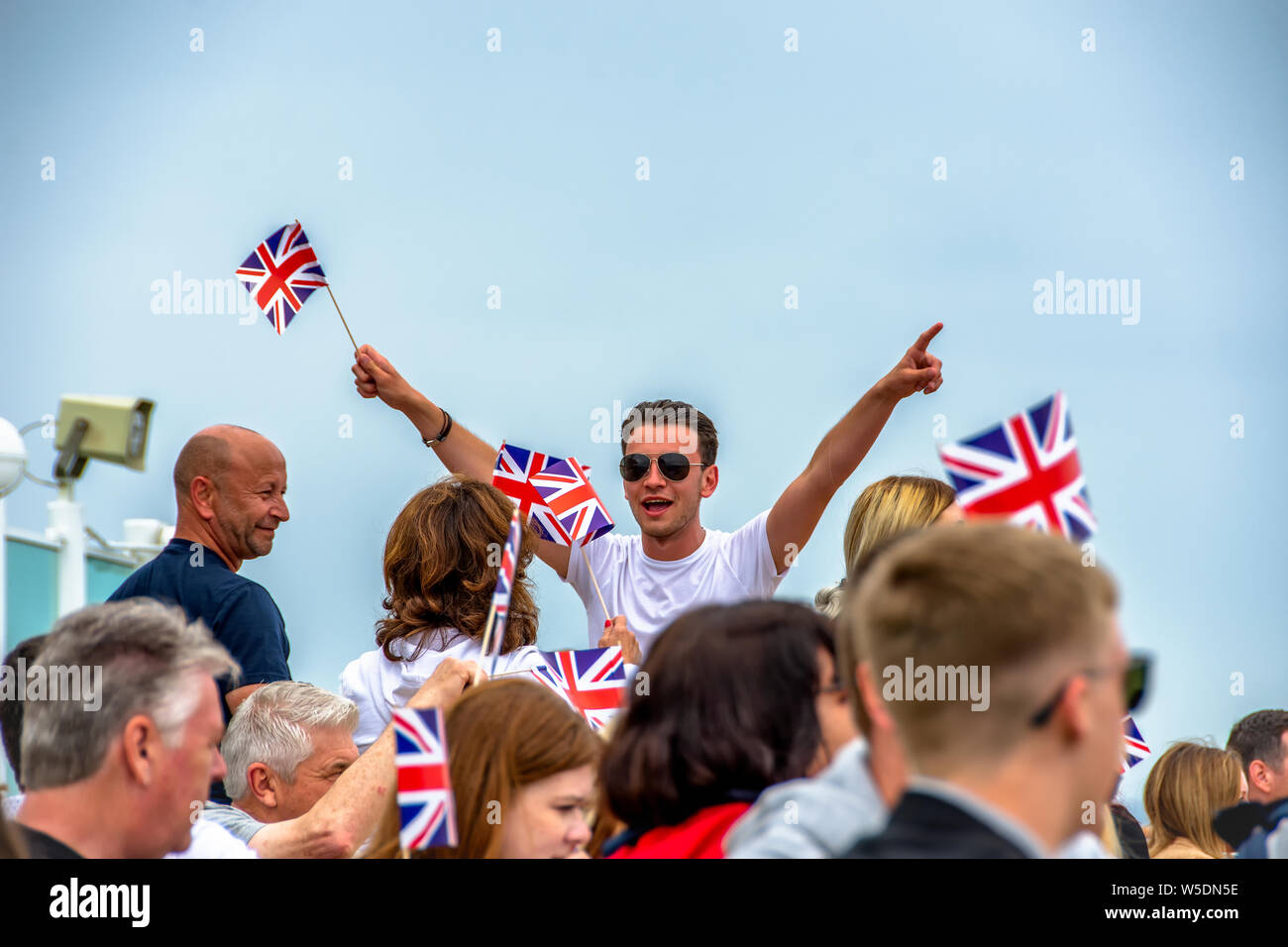 Mann dirigiert die Menge, winkt Union Jack Flaggen Stockfoto