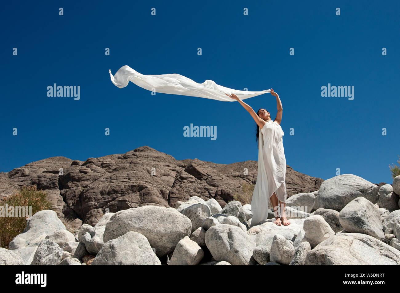 Schöne spirituelle asiatischen koreanisch-amerikanischen Frau in die Wüste trägt ein schlichtes weißes Kleid. Der Wind ist mit ihrem weißen Schal Overhead. Stockfoto