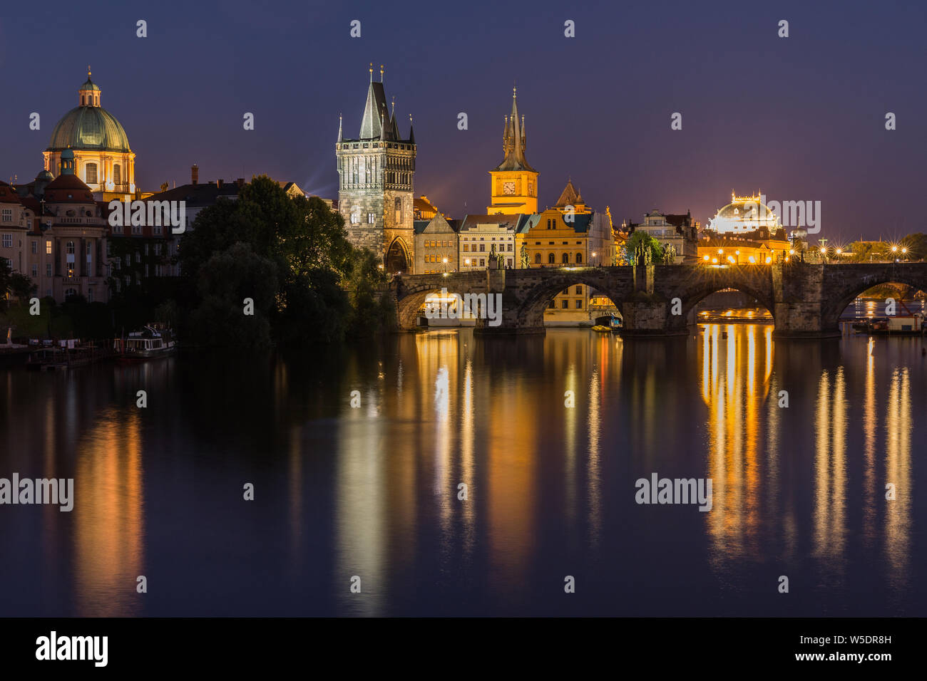 Charles Bridge bei Nacht in Prag. Turm und die historische steinerne Brücke über die Moldau mit Beleuchtung zwischen der Altstadt und der Kleinseite. Reflexionen Stockfoto