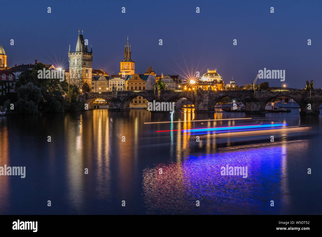 Altstadt Turm und die historische steinerne Brücke mit Beleuchtung und Reflexionen aus dem Schiff auf dem Wasser. Prag mit Charles Bridge bei Nacht. Panoramaaussicht Stockfoto
