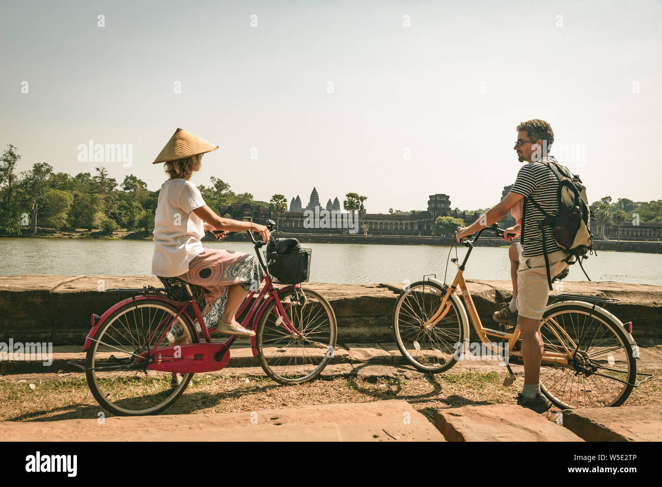 Touristische paar Radfahren im Tempel Angkor, Kambodscha. Angkor Wat Hauptfassade auf Wasser Teich wider. Umweltfreundliche Tourismus reisen. Getönt Stockfoto