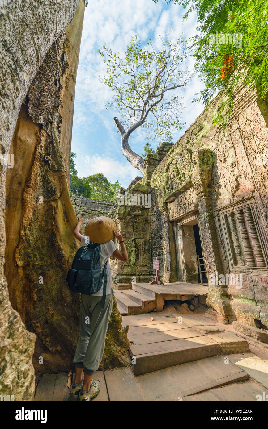 Eine touristische besuchen Angkor Ruinen inmitten Dschungel, Tempelanlage Angkor Wat, Reiseziel Kambodscha. Frau mit traditionellen Hut, Ansicht von hinten. Stockfoto