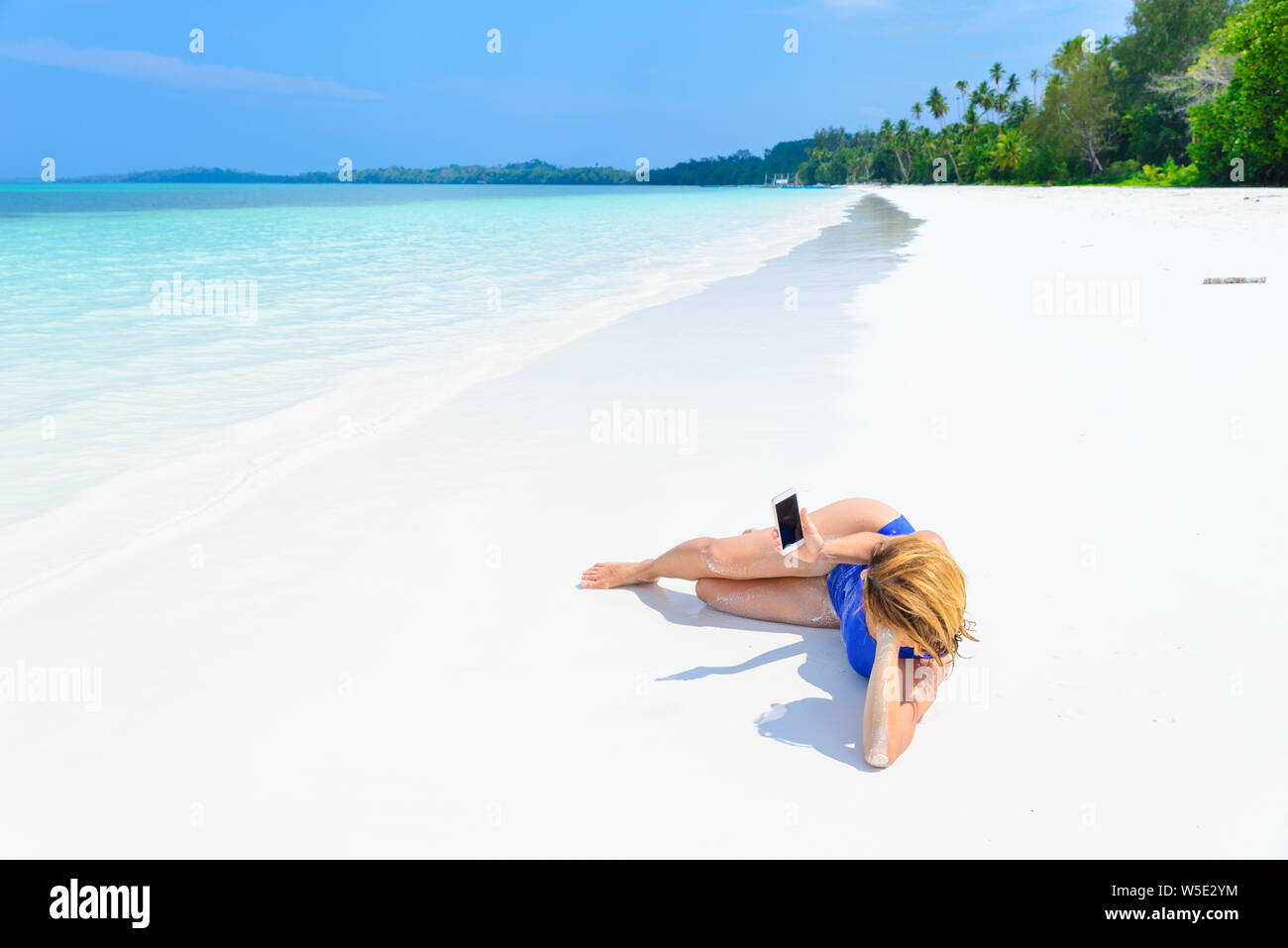 Frau mit smart phone Erholung am weißen Sandstrand, echte Menschen rund um die Welt reisen. Indonesien tropischen Destination, Lebensstil teilen Soziale Stockfoto