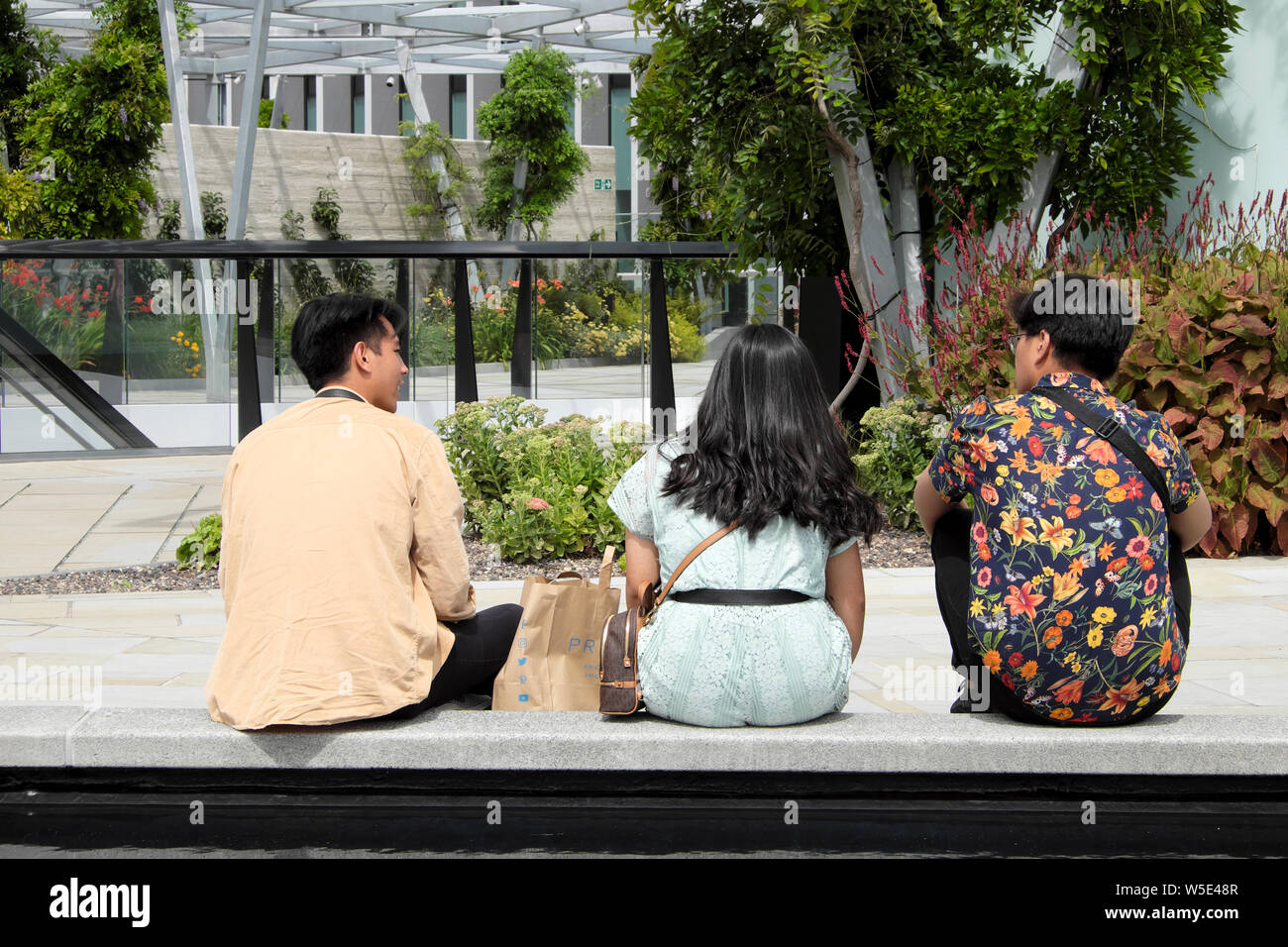 Junge Chinesen sitzen auf einer Bank auf der Terrasse im Garten in 120 in der Fenchurch Street in London England, Großbritannien KATHY DEWITT Stockfoto