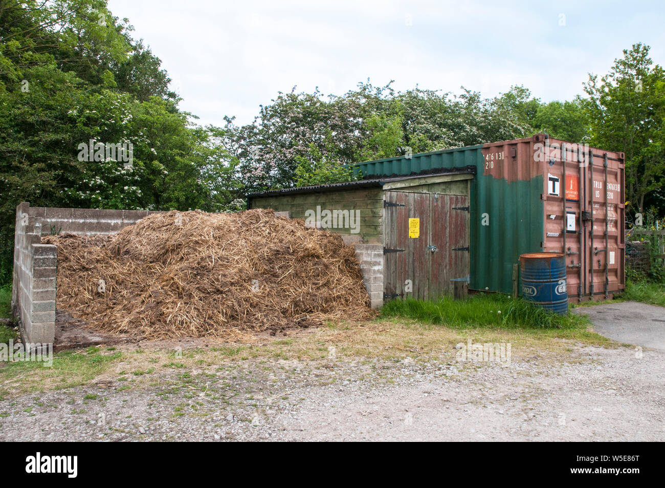 Gülle oder Mist Heap im muck Bay auf Zuteilung Seite neben einem Lagerschuppen und Metall Container Stockfoto