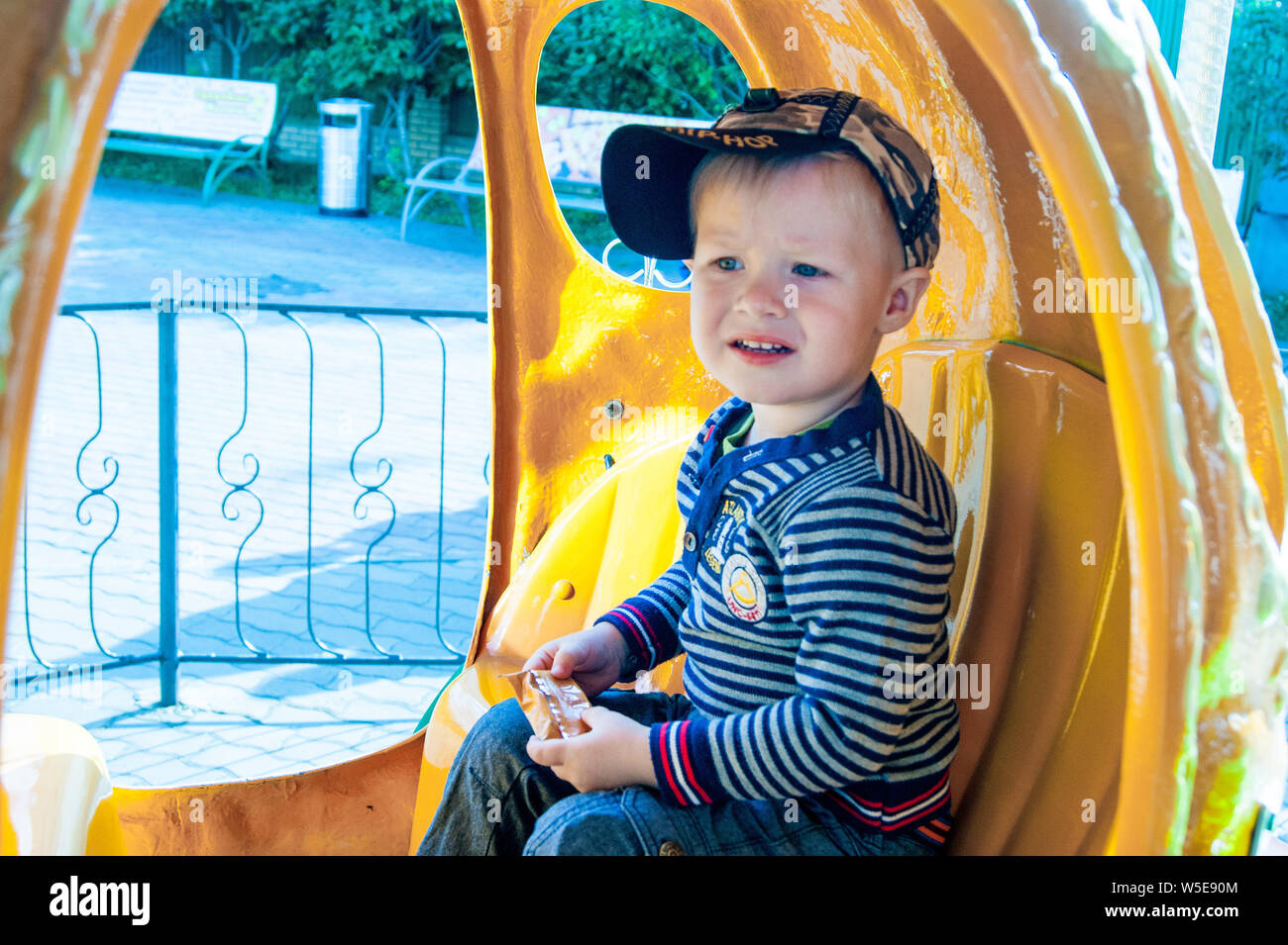 Ein 3-jähriger blonder und blauäugiger Junge reitet ein Merry-go-round in einem gelben Kürbis. Spaß, Aktivität, Eindrücke, Emotionen. Kalten Sommer oder Anfang Herbst Stockfoto