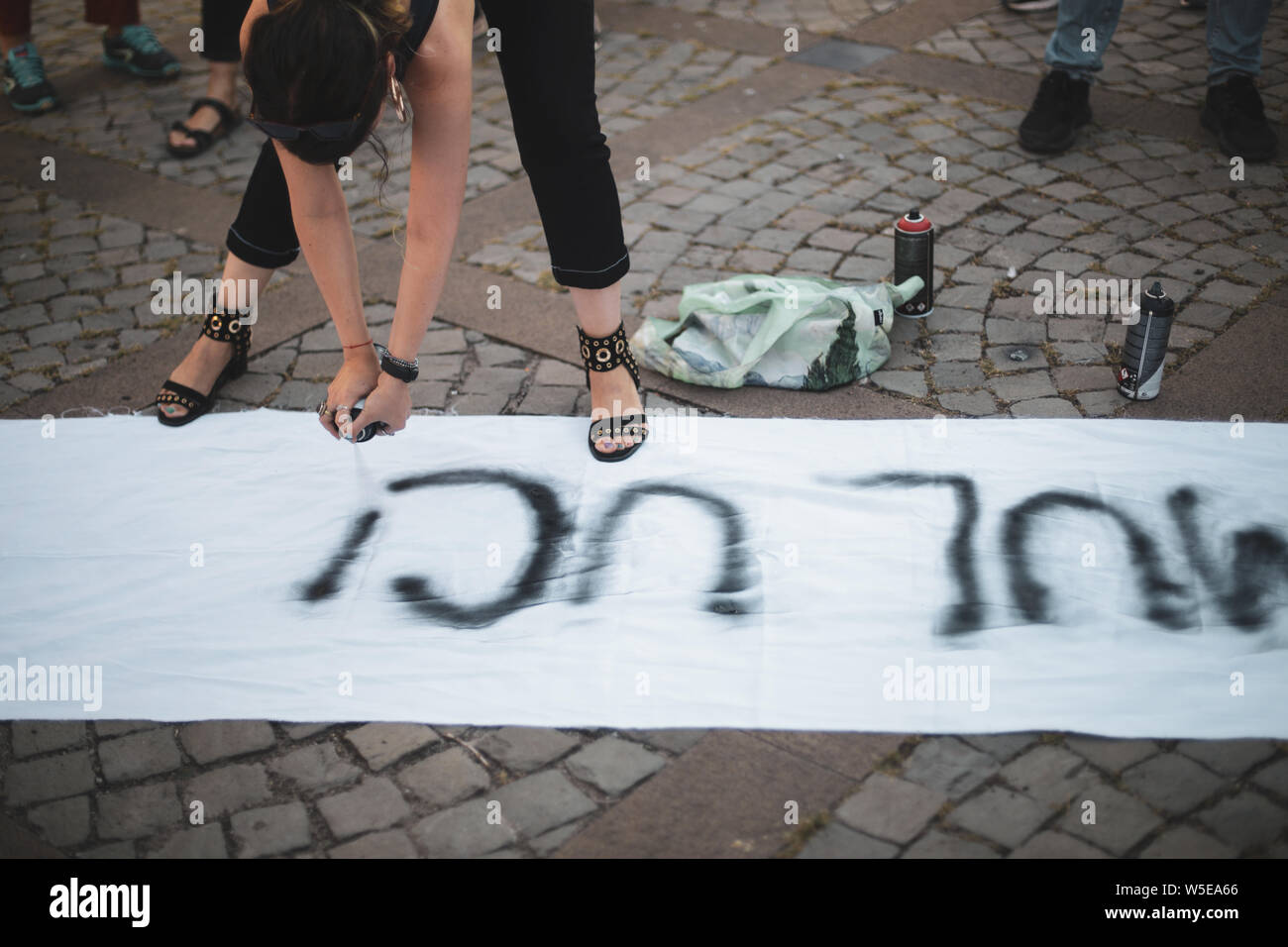 Details mit den Händen einer jungen Frau mit einem schwarzen Lack Spray eine feministische Botschaft auf ein Stück Tuch whitee Stockfoto