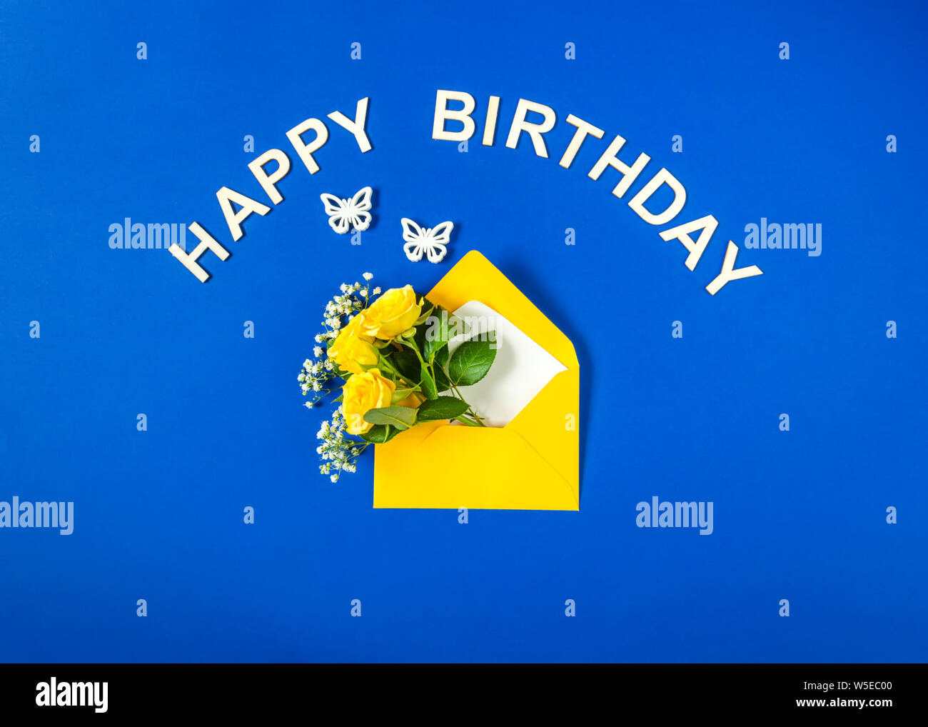 Gelbe Rosen und weißen Gypsophila im Umschlag close-up auf blauem Hintergrund. Text Happy Birthday, weiße Schmetterlinge. Ansicht von oben, flach. Für bi-Vorlage Stockfoto