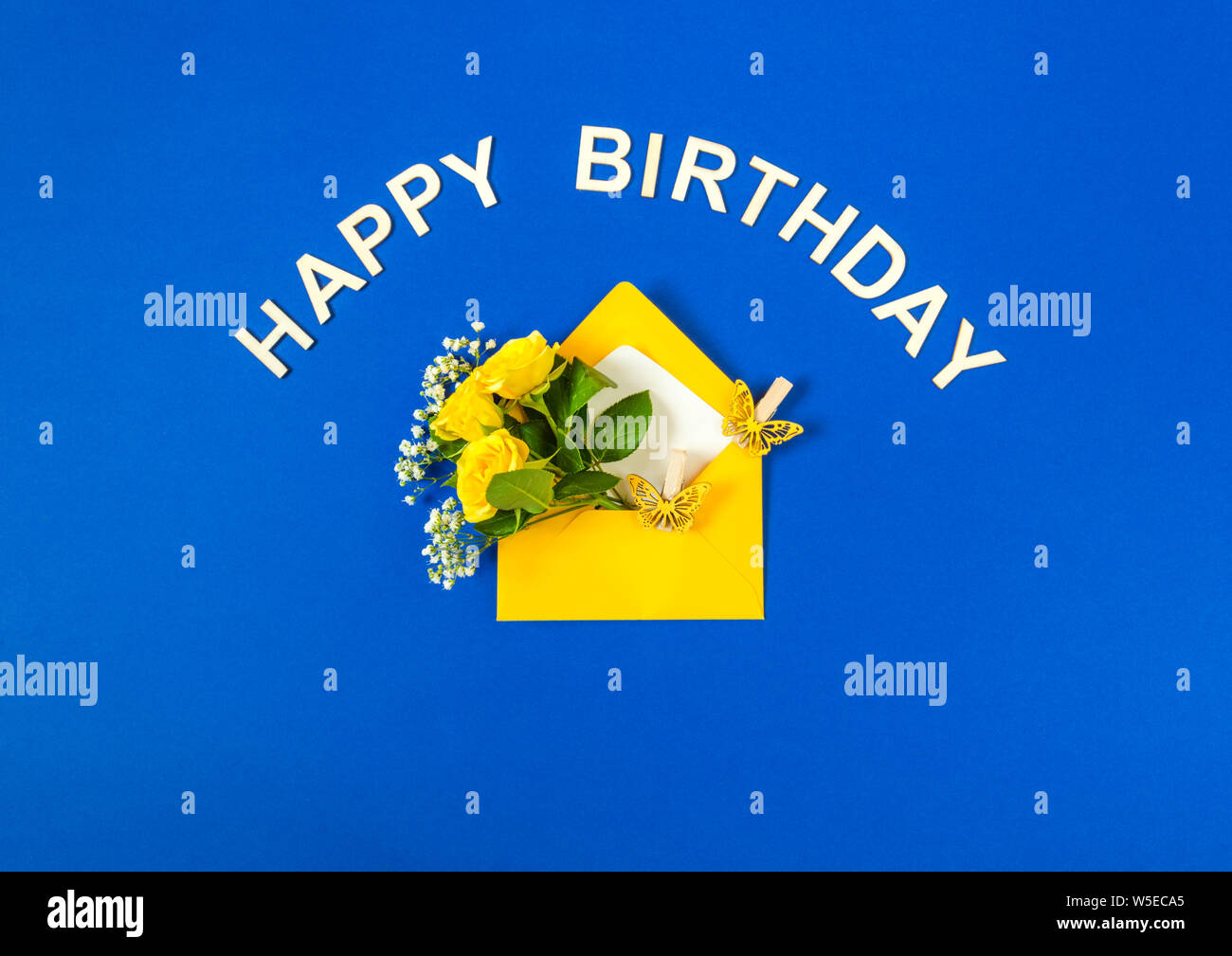 Gelbe Rosen und weißen Gypsophila im Umschlag close-up auf gelben Hintergrund. Text Happy Birthday, Holz- briefe. Ansicht von oben, flach. Für bir Vorlage Stockfoto