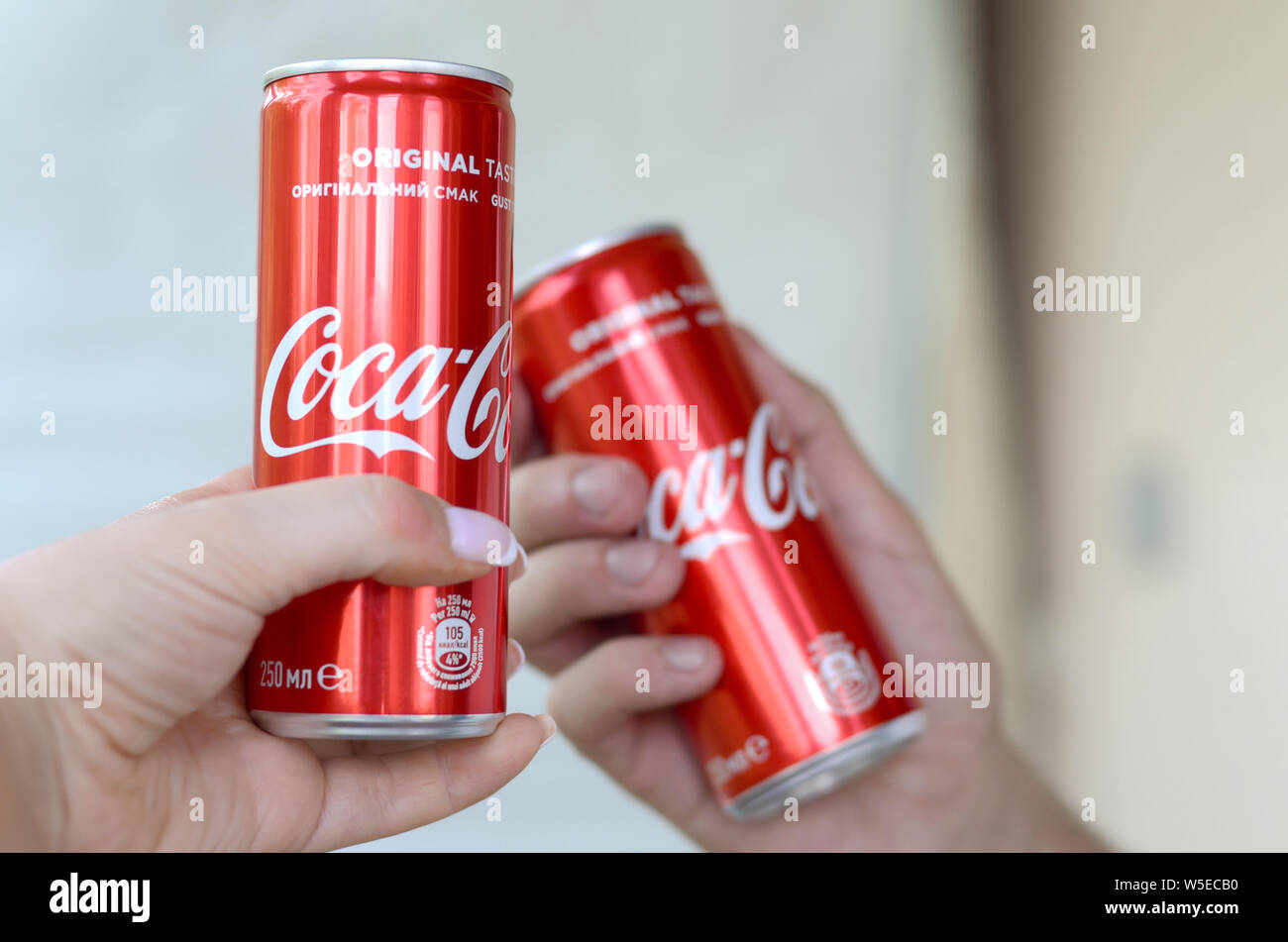 Charkow, Ukraine - 15. JULI 2019: Paar Hände wirft rot Coca Cola Dosen in der Garage. Coca Cola ist die bekannteste Marke der Kohlensäure nicht-alco Stockfoto