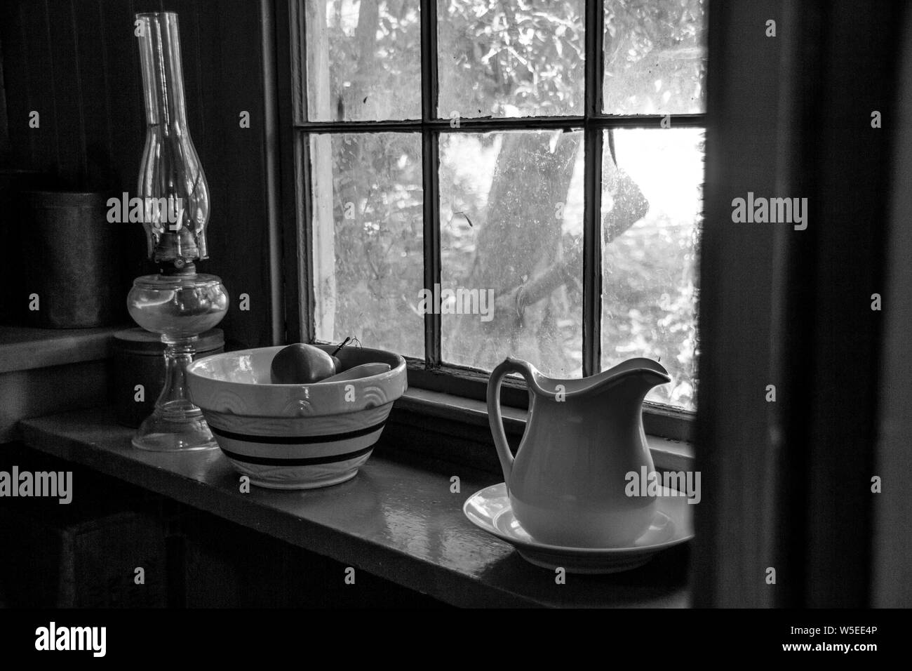 Einfachere Zeiten: Schwarz und Weiß Foto, natürliche Beleuchtung durch einen Vintage Fenster einer Laterne, Schale, Krug in Benicia, Kalifornien. Stockfoto