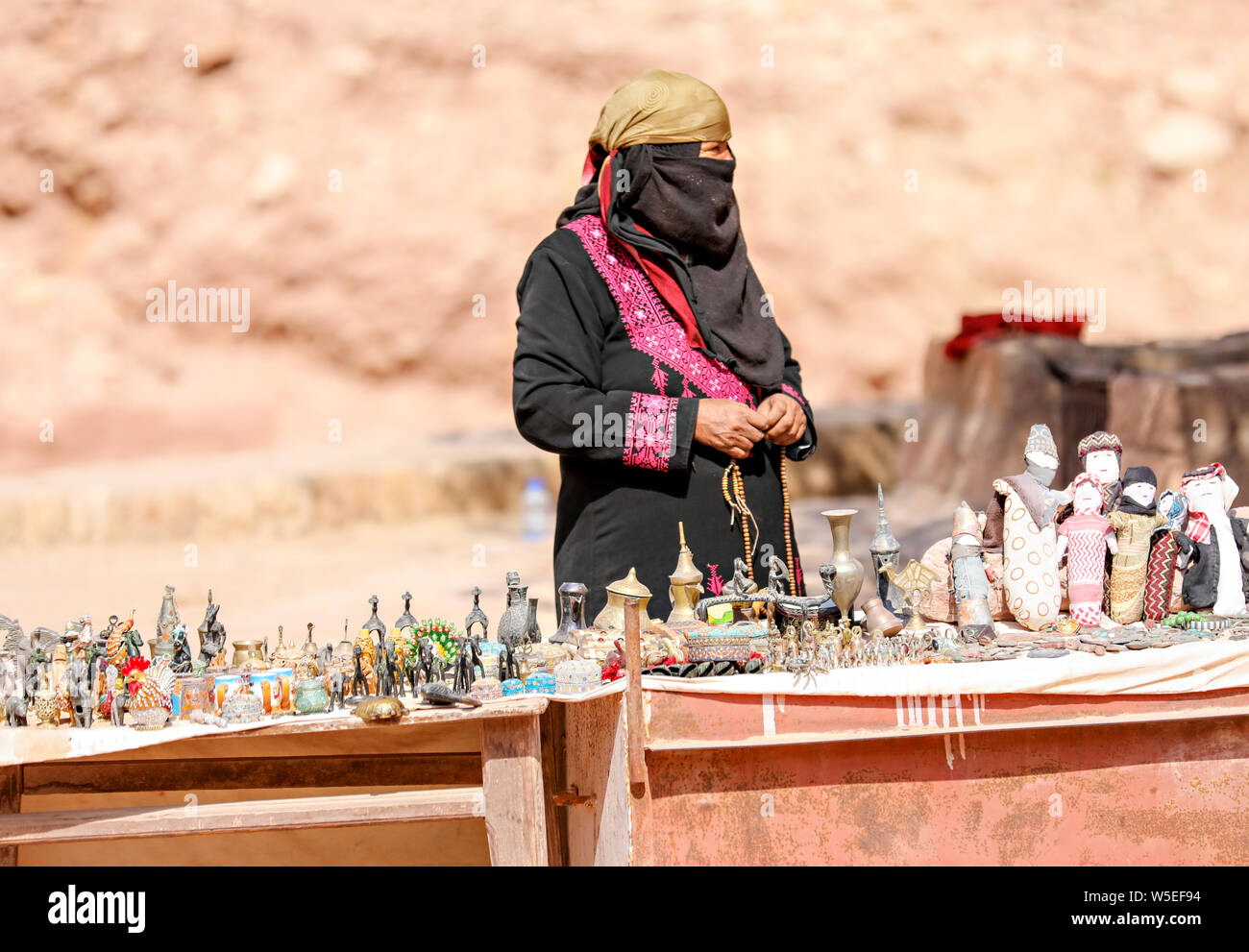 Muslimische Frau in traditioneller Kleidung, vollständig abgedeckt, Verkauf ihrer Waren an einem Stand in Petra, Jordanien. Stockfoto