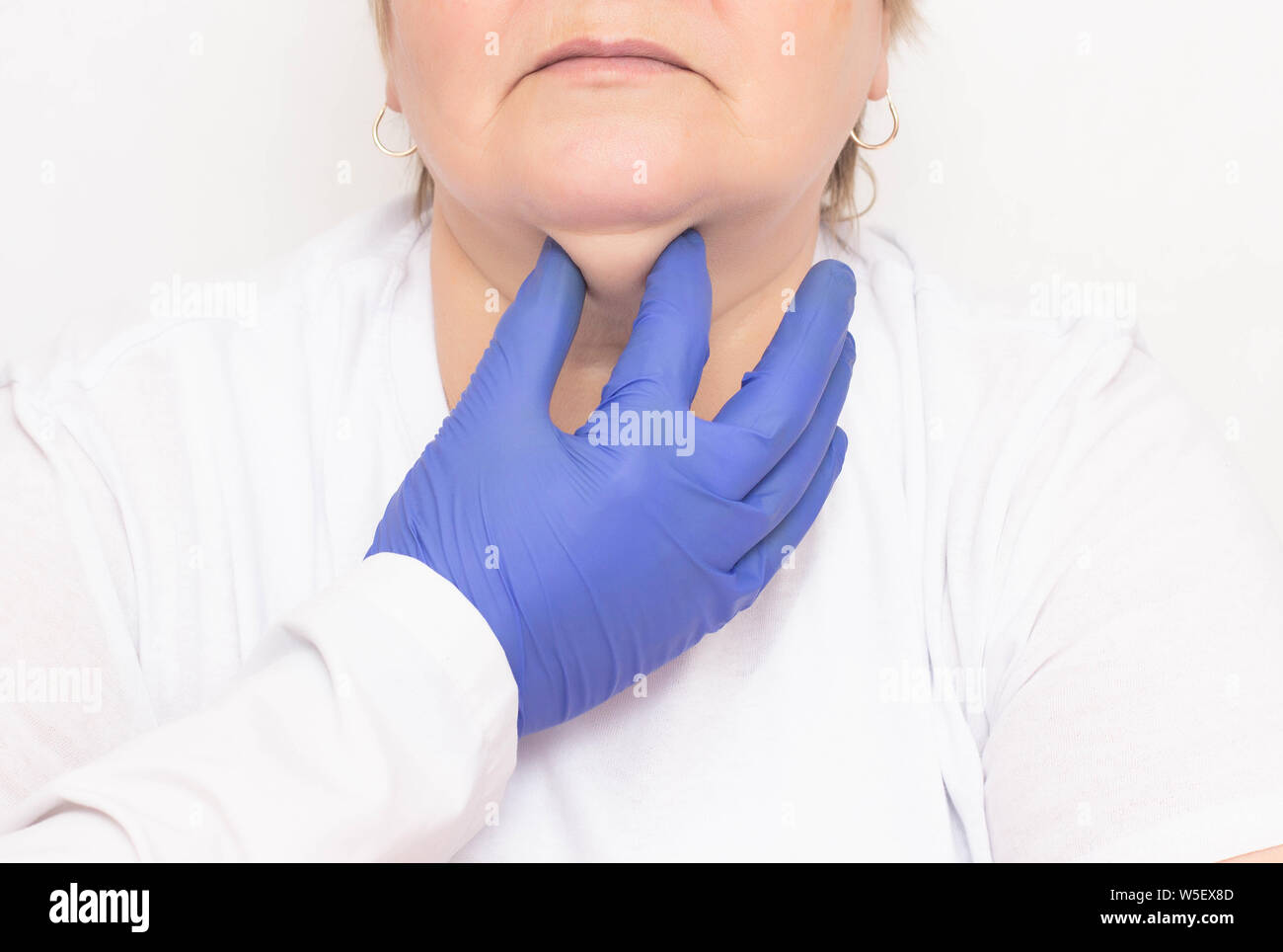 Ein plastischer Chirurg untersucht eine gealterte Frau zu ziehen und loszuwerden, Falten und Doppel Kinn, weißer Hintergrund, kosmetologe Stockfoto