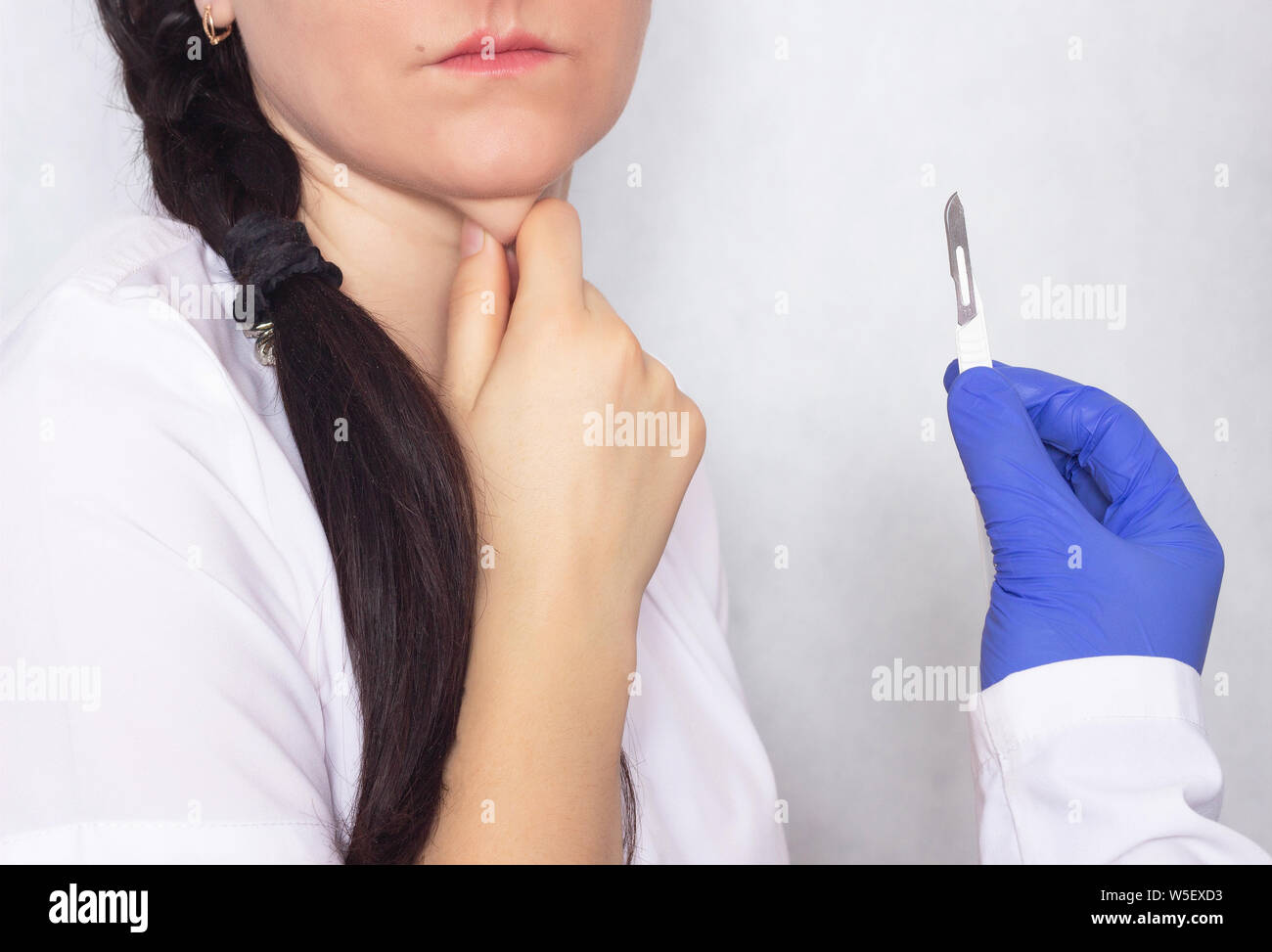 Plastischer Chirurg Holding ein Skalpell in der Hand vor dem Hintergrund  der ein Mädchen mit einem doppelkinn, die Erneuerung eines Doppelkinn in  Kunststoff surger Stockfotografie - Alamy