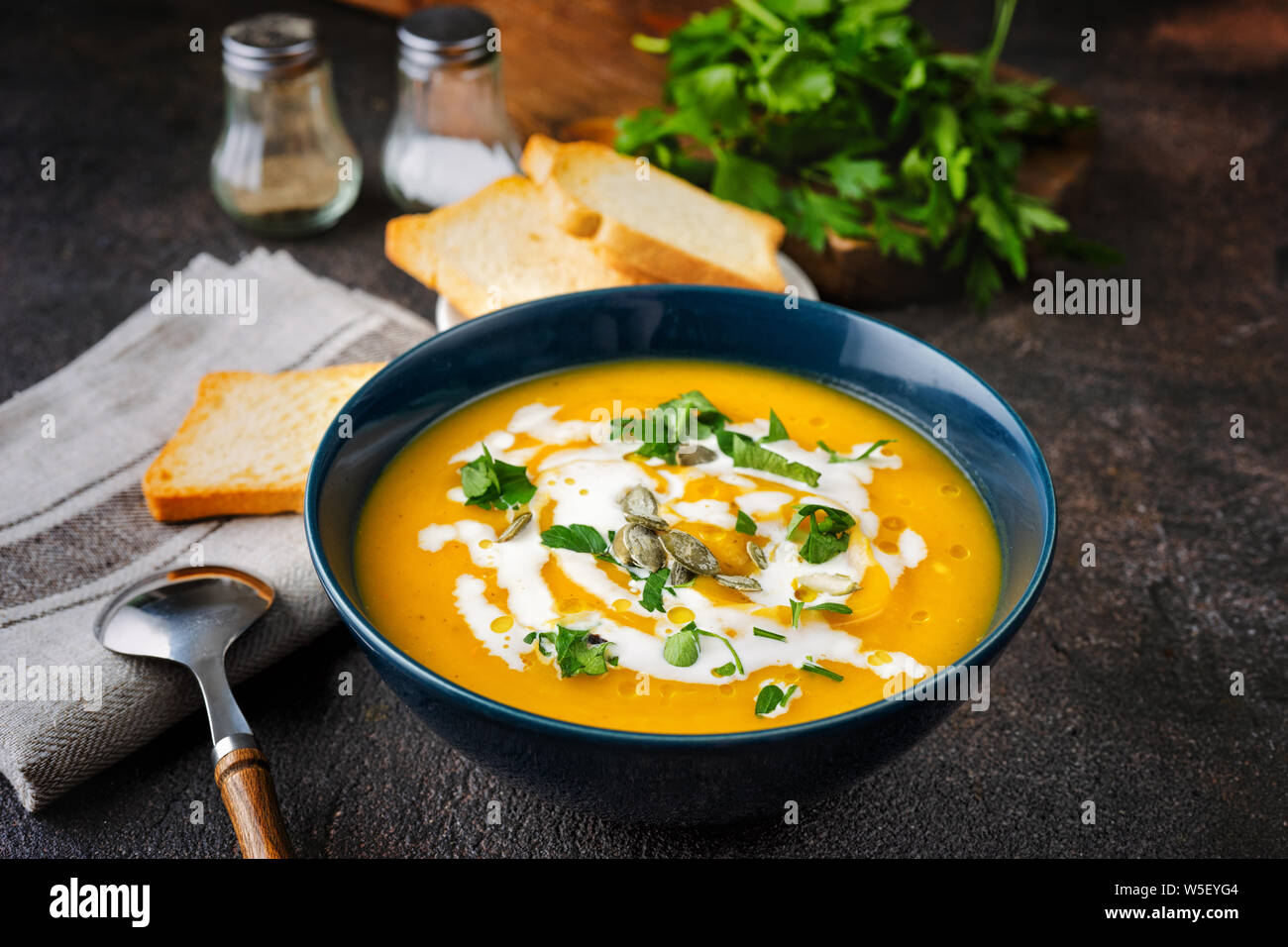 Kürbissuppe mit Sahne und Petersilie auf dunklen rustikalen Hintergrund Stockfoto Kürbissuppe mit Sahne und Petersilie auf dunklen rustikalen Hintergrund Stockfoto