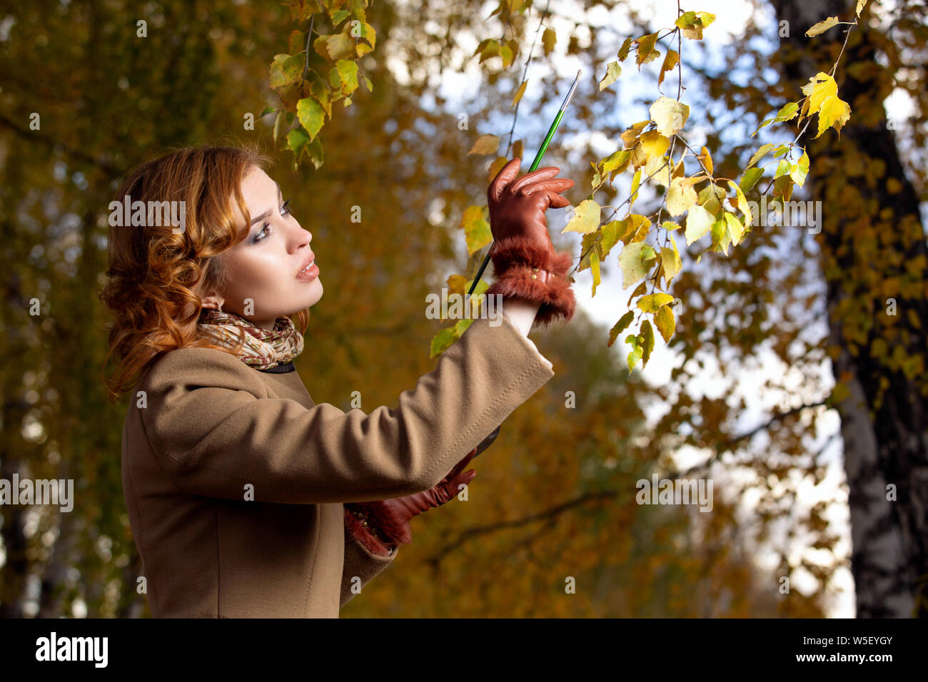Schöne Frau mit Palette und Pinsel Lacke Farben Blätter an den Bäumen Stockfoto